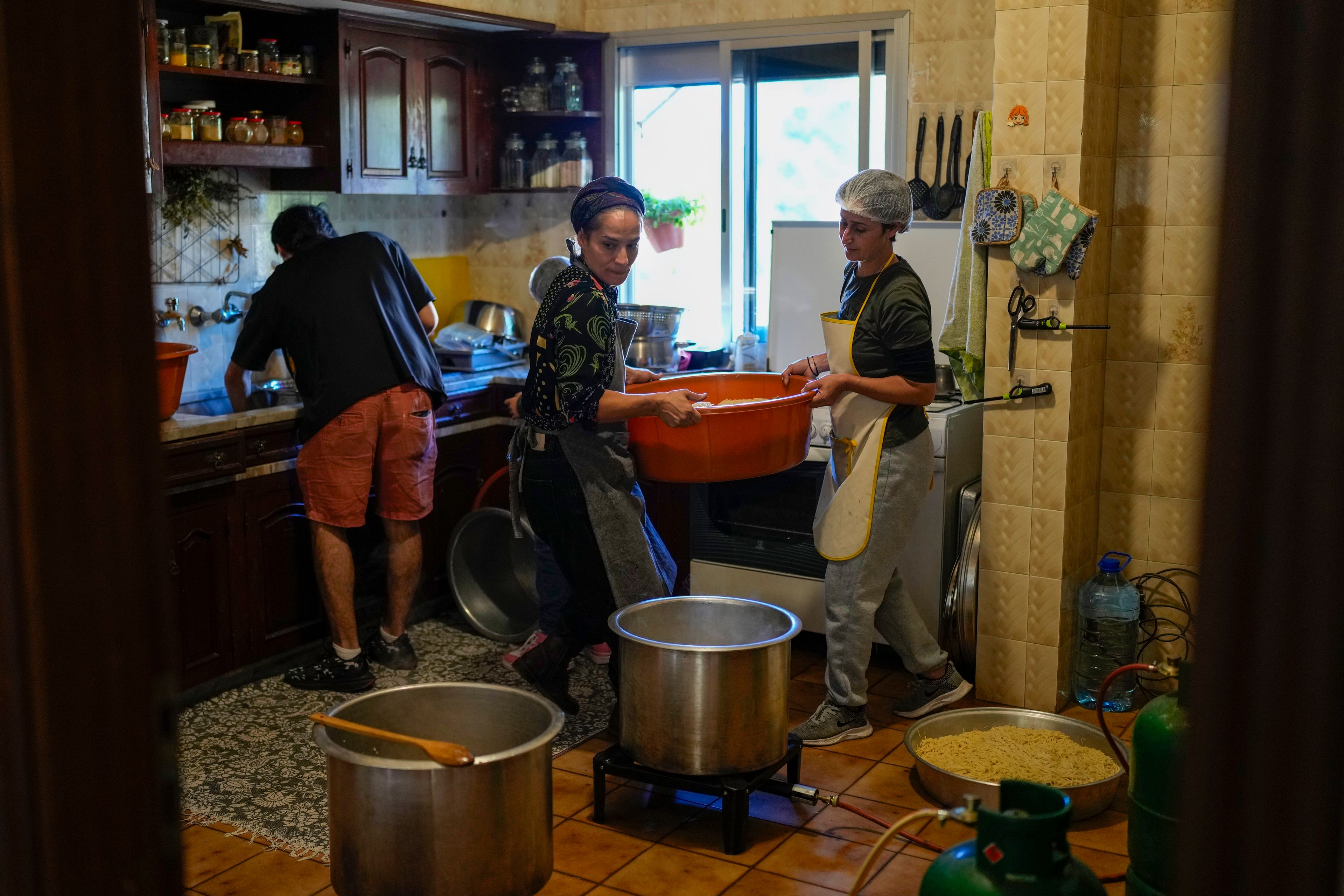 Volunteers prepare meals at a women's art center that was turned into a kitchen for displaced people who fled southern Lebanon amid the ongoing Hezbollah-Israel war, in the town of Aqaibe, northern Lebanon, Thursday, Oct. 24, 2024. (AP Photo/Hassan Ammar)