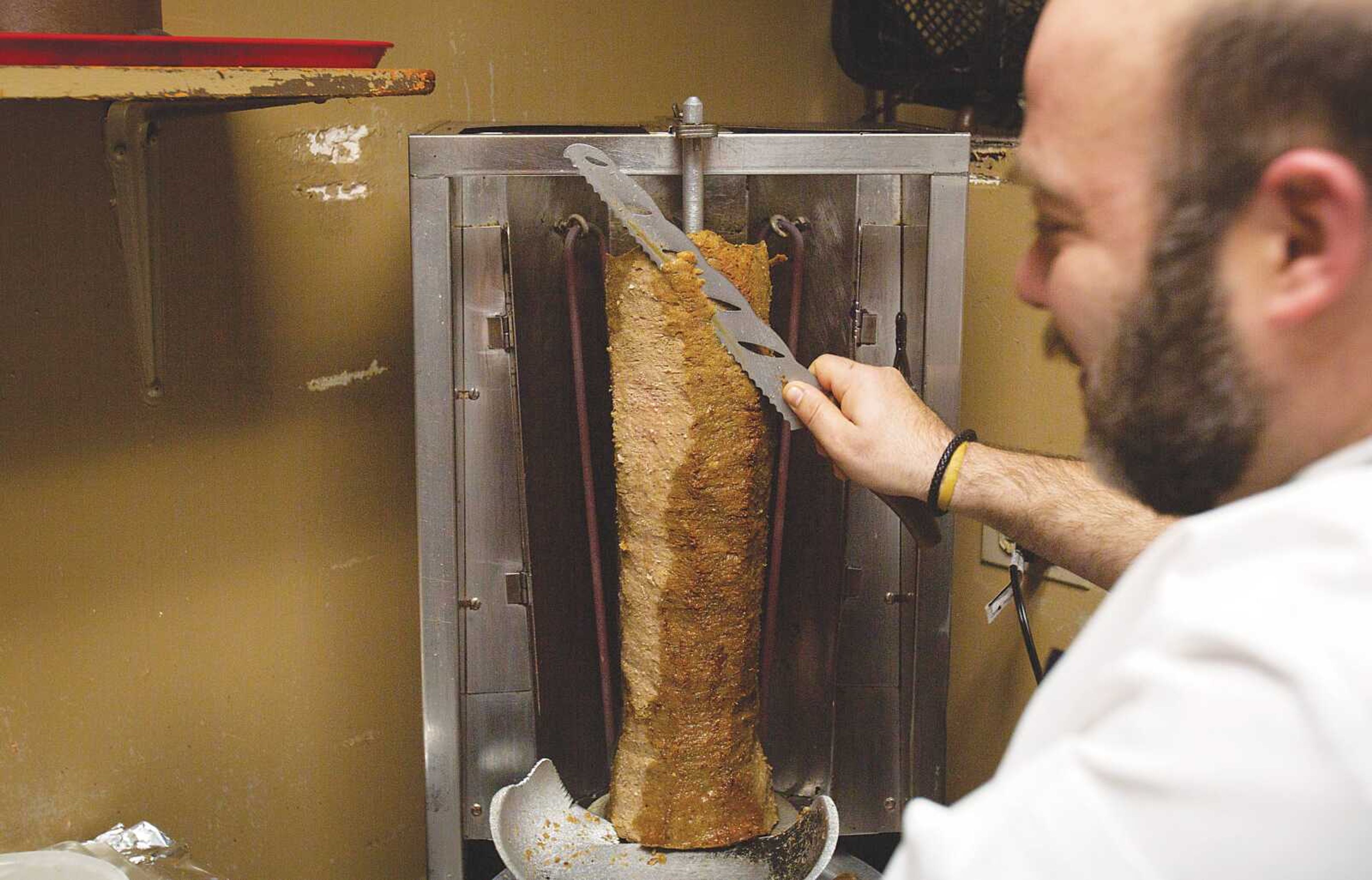 Georgios Kastanias slices gyro meat from the rotating spit in the kitchen at Zoi's Gyros Corner in Cape Girardeau.