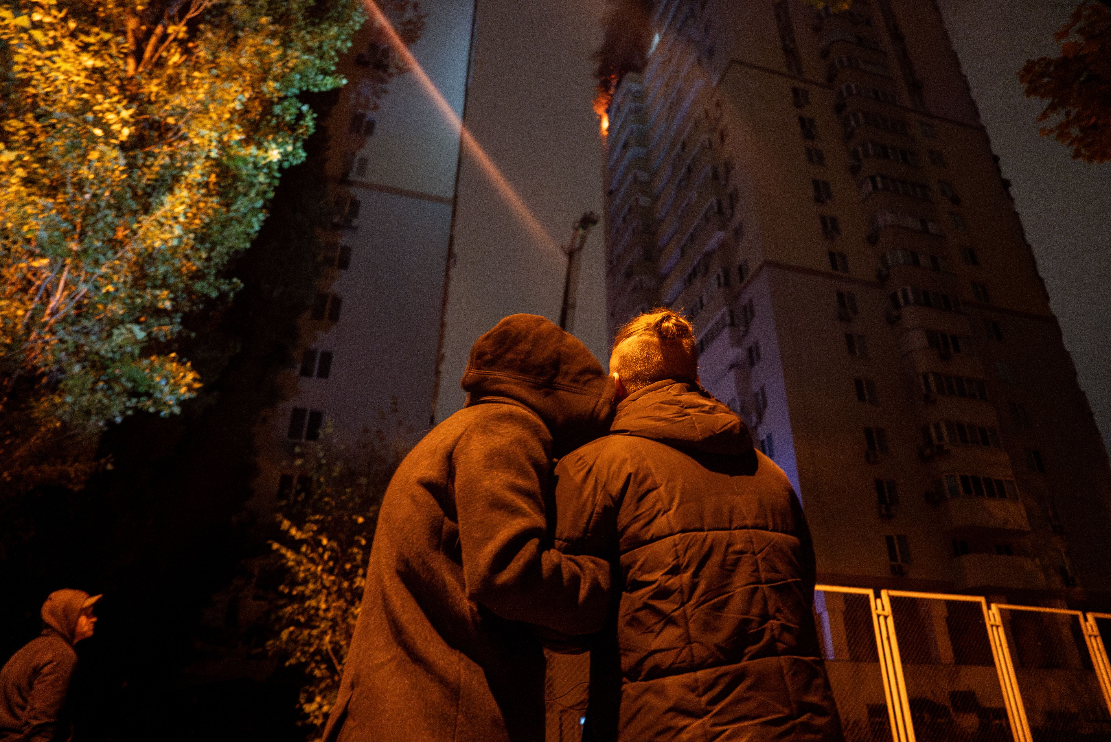 A couple comforts each other while looking at the fire in a residential building after the attack of Russian drones in Kyiv, Ukraine, Friday, Oct. 26, 2024. (AP Photo/Alex Babenko)