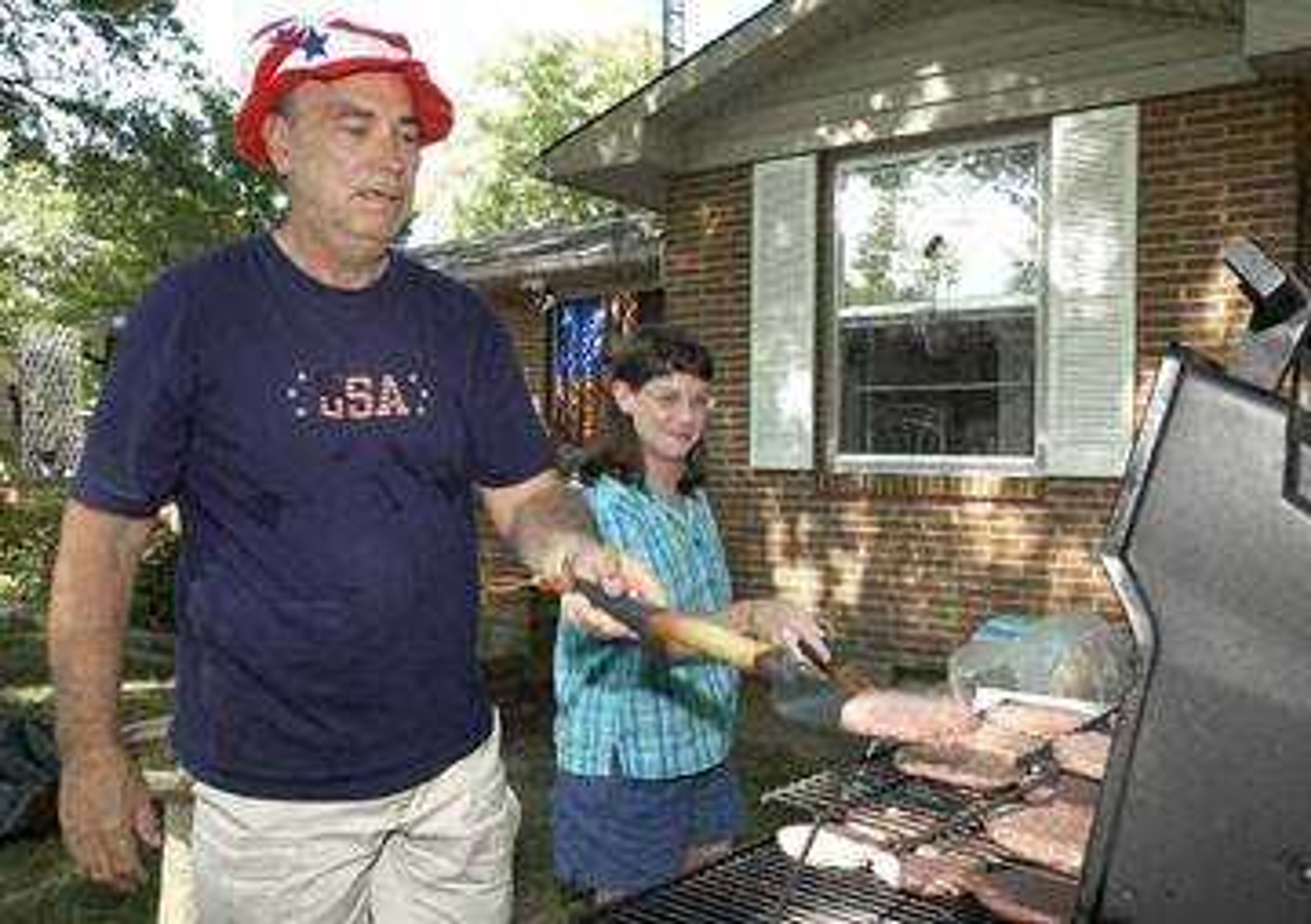 Richard Harrington (L) and Julie Williams (R) of Cairo, Ill. kept an eye on the grill during Friday's, July 4, 2003, family cookout at Harrington's Cape Girardeau home.