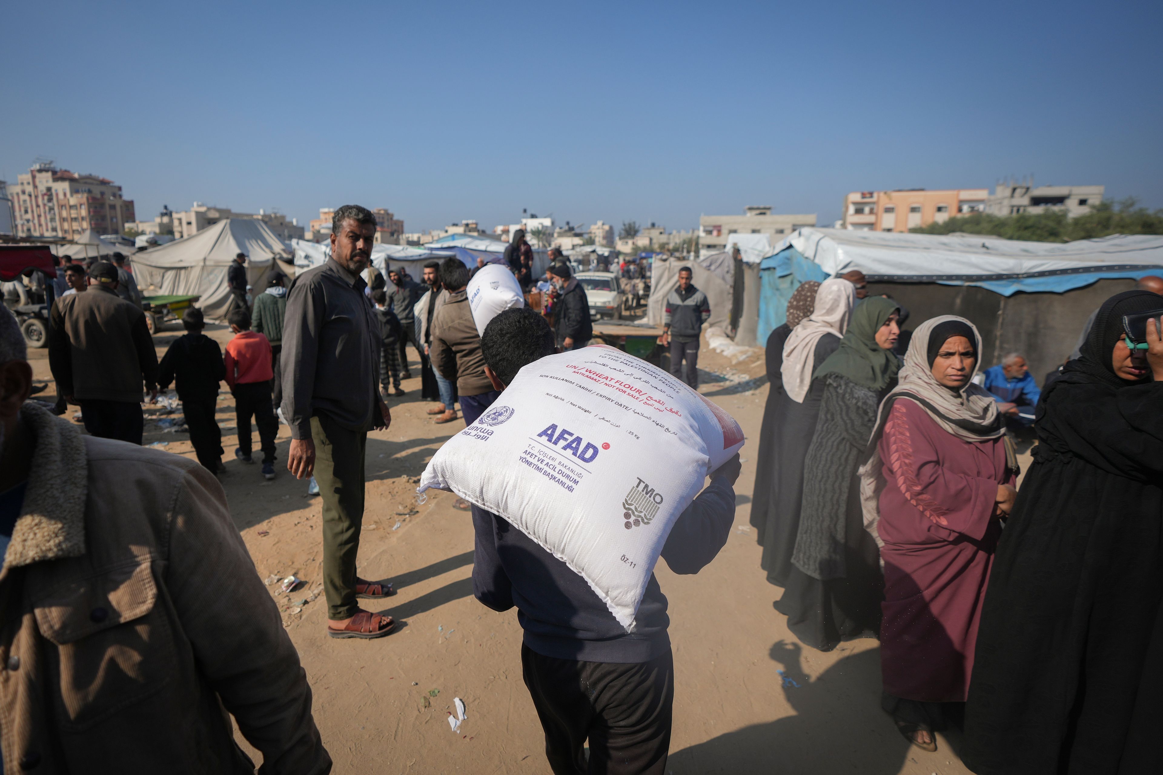 A man carries a sack of donated flour distributed by UNRWA at the Nuseirat refugee camp, Gaza Strip, Tuesday Dec. 3, 2024.(AP Photo/Abdel Kareem Hana)