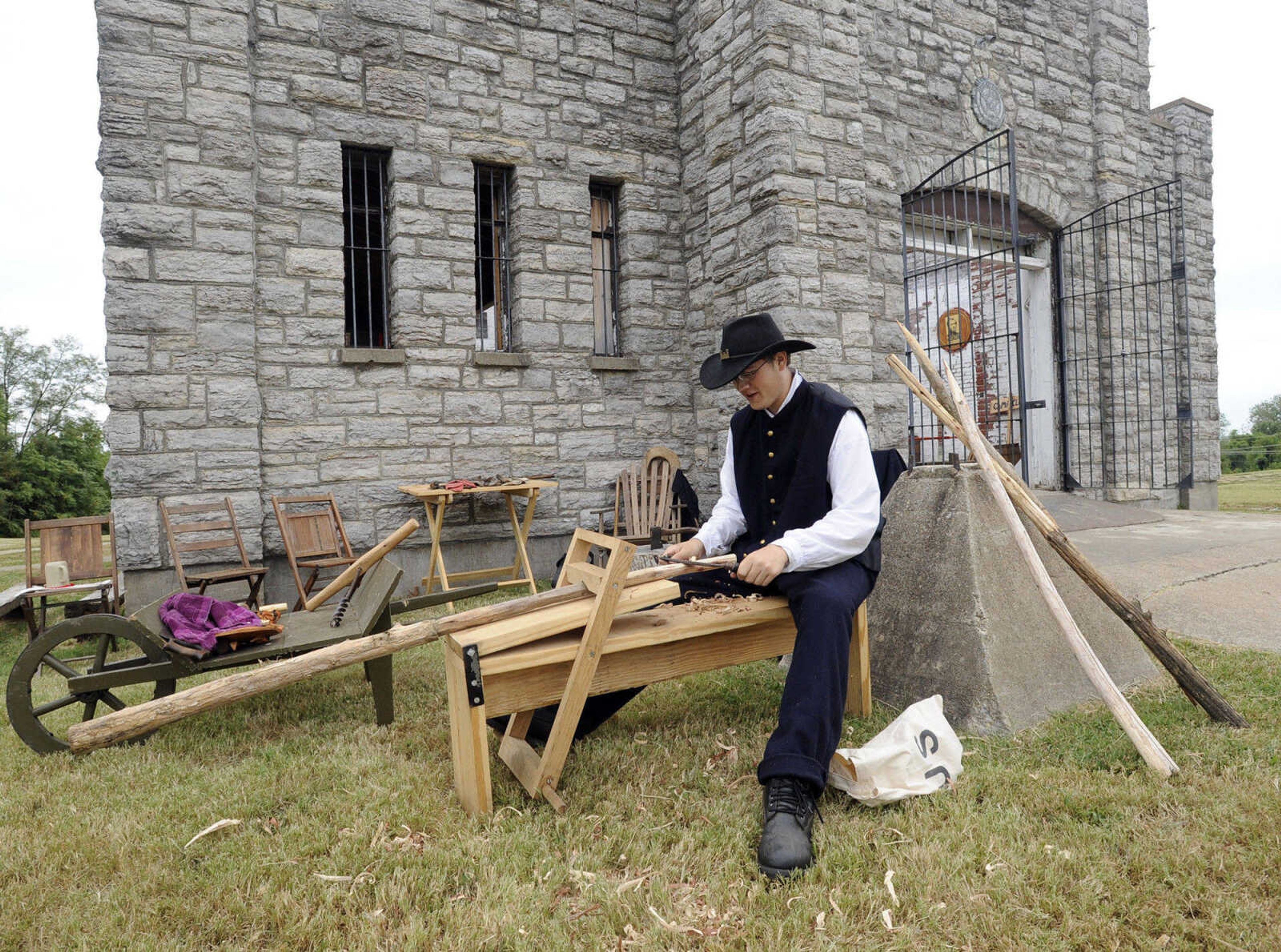 Turner Brigade member Steven Meyer works with a drawknife on a sawhorse at Fort D.