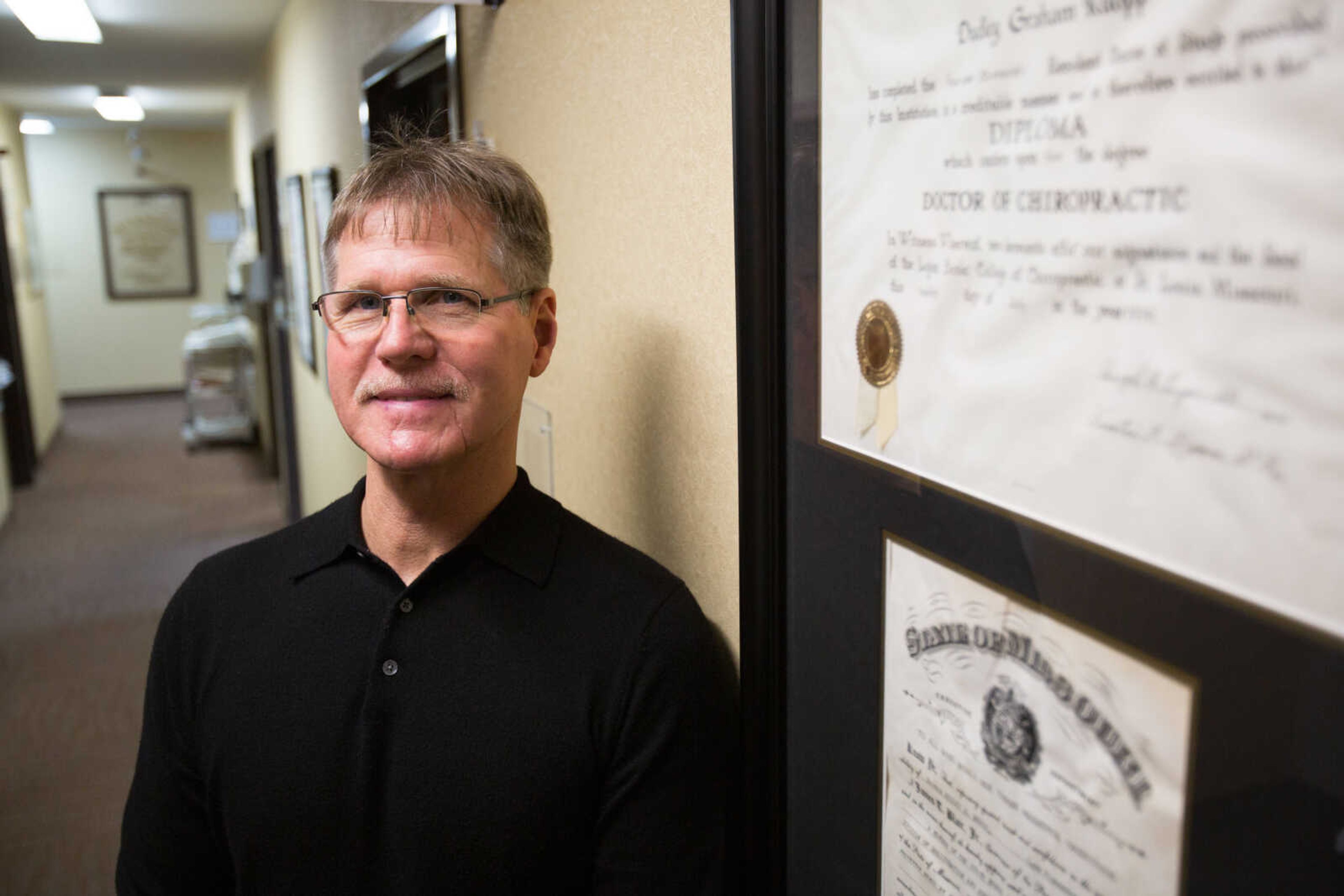 Dr. Jack Ruopp of Hudson Chiropractic stands near his father's framed diploma dating from 1939.