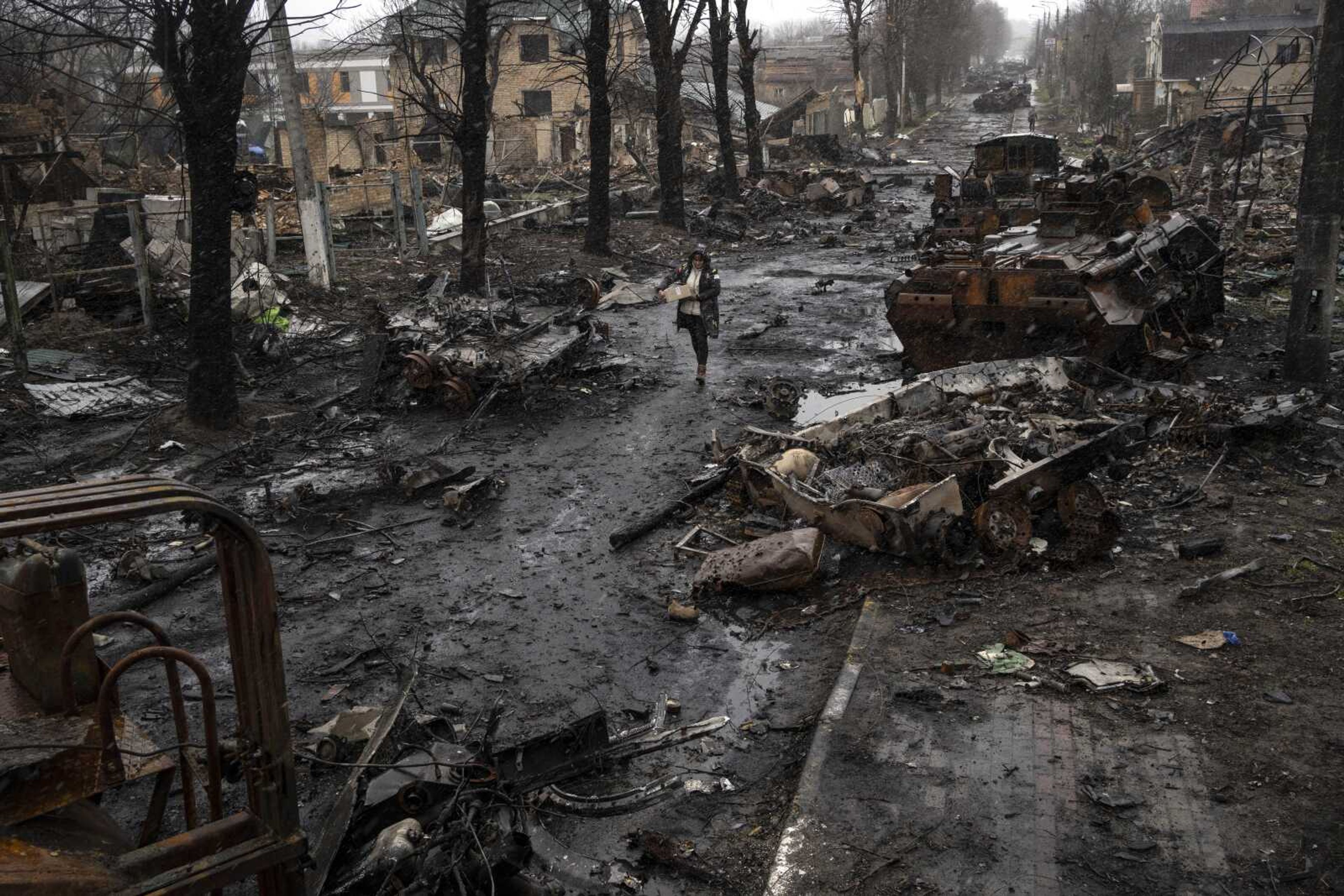 A woman walks amid destroyed Russian tanks Sunday in Bucha, in the outskirts of Kyiv, Ukraine.