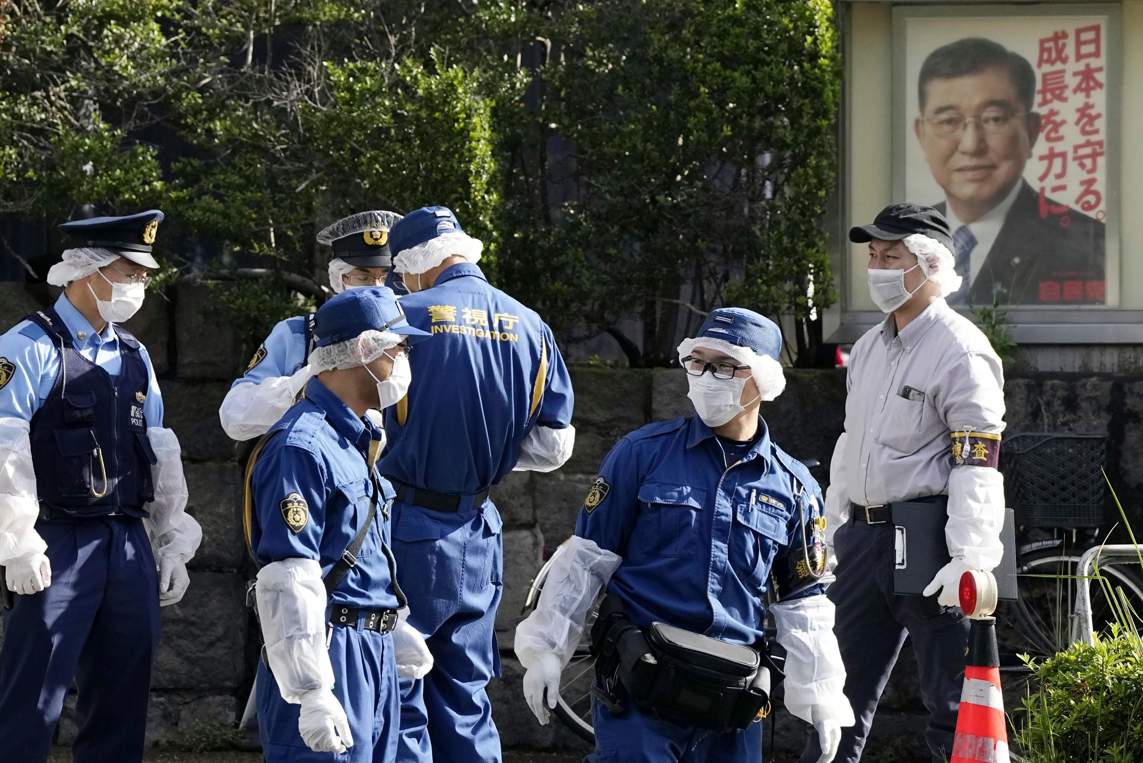 Police officers gather near the headquarters of Japan's ruling Liberal Democratic Party with a poster of Japan's Prime Minister and the party's head Shigeru Ishiba on display after a man threw firebombs into the headquarters in Tokyo Saturday, Oct. 19, 2024. (Kyodo News via AP)