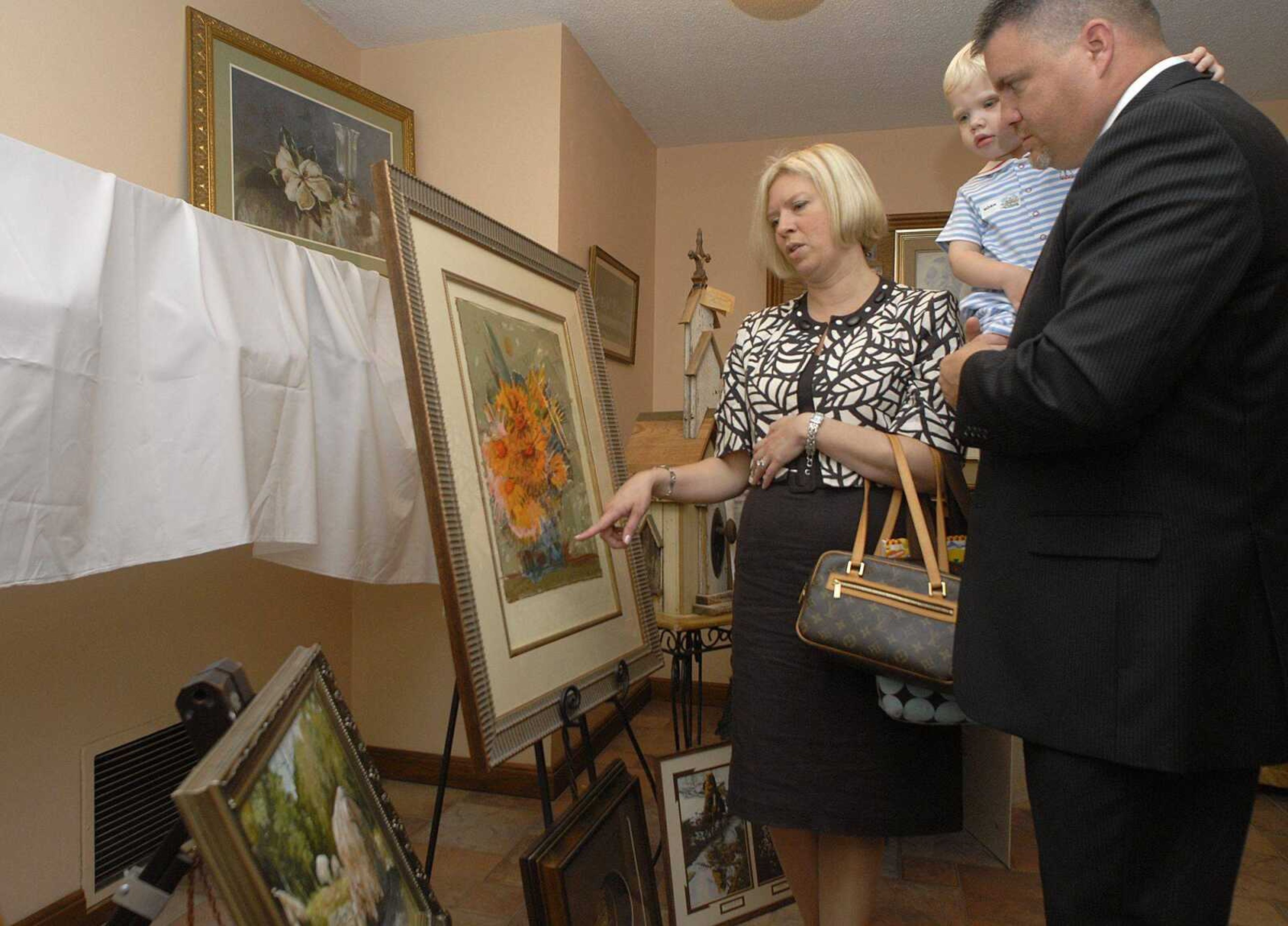 Kara and Mike Skelton with their son, Grant, look at some of the artwork on display at Grace United Methodist Church that will be available at an auction to benefit the church's Mozambique Initiative. (Fred Lynch)