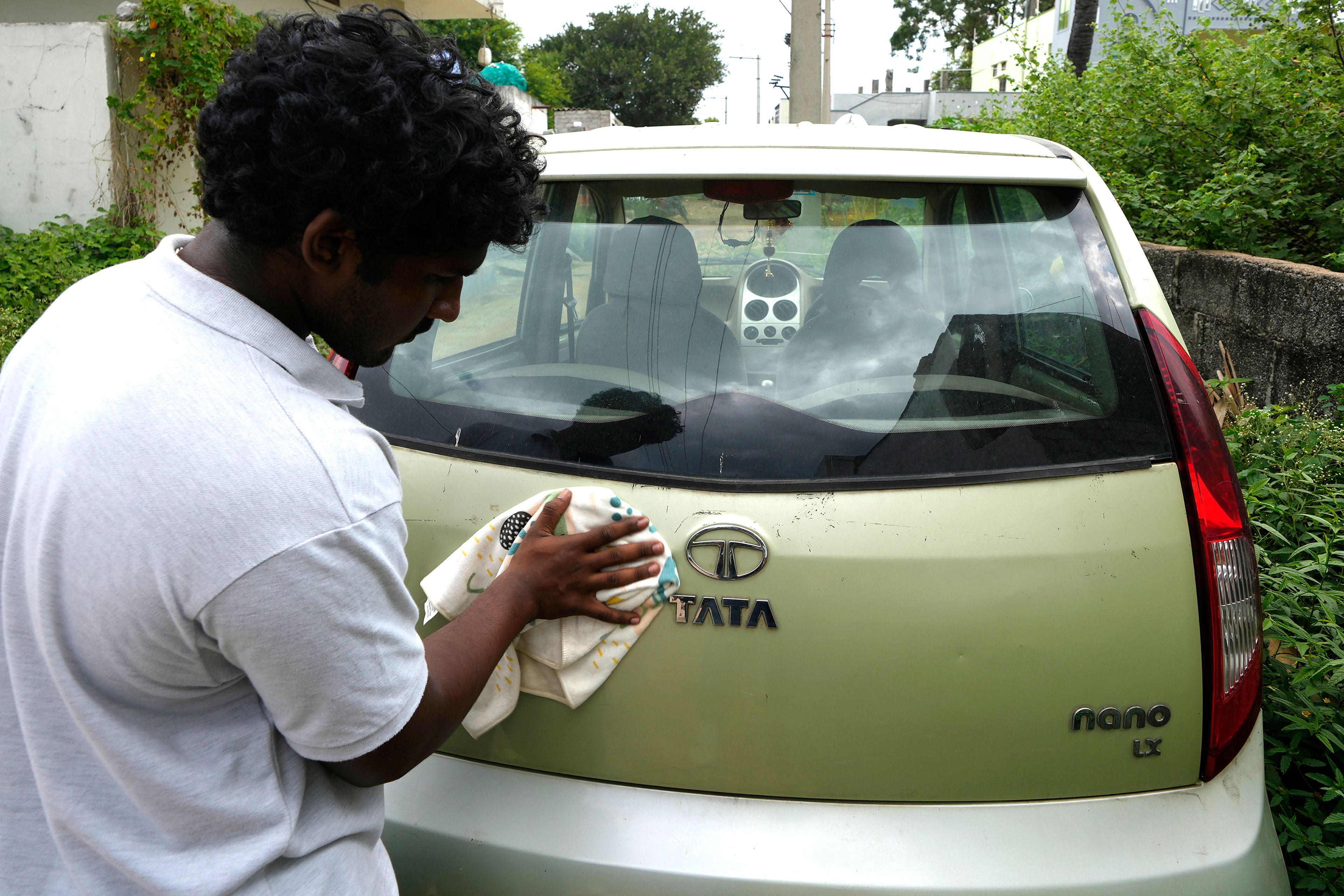 A man cleans his Tata Nano car in Hyderabad, India, Thursday, Oct. 10, 2024. (AP Photo/Mahesh Kumar A.)