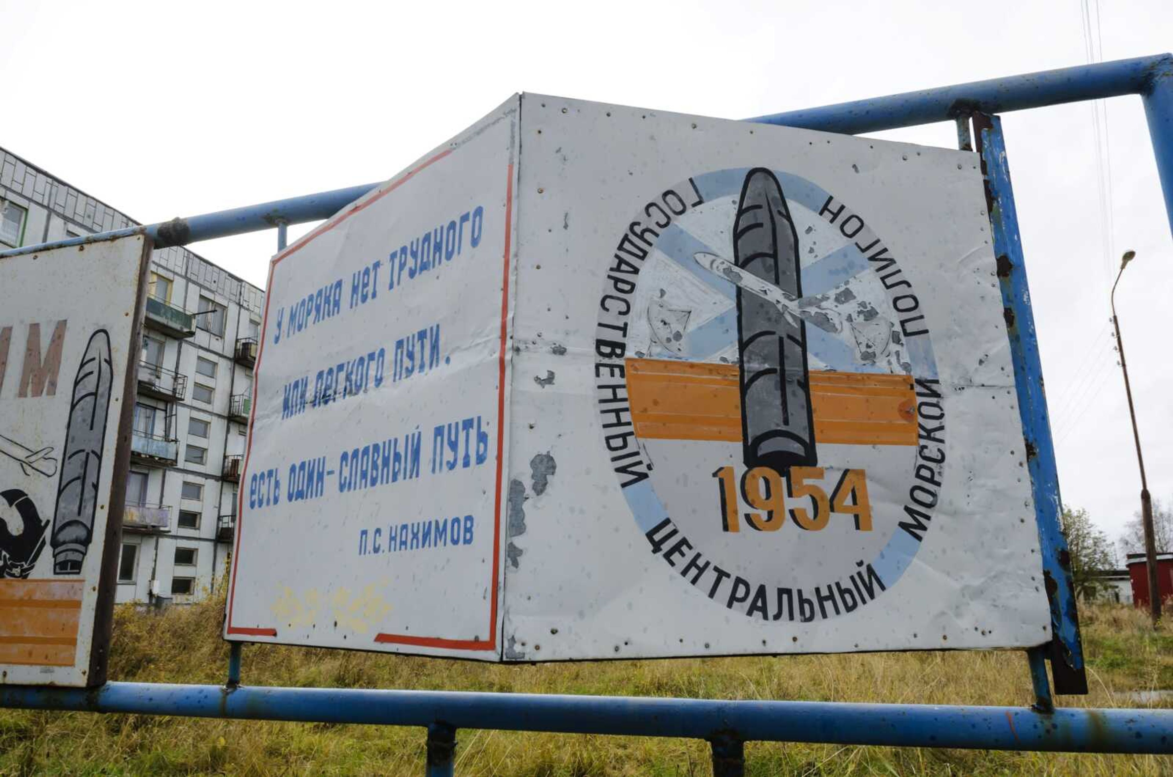 A billboard that reads "The State Central Navy Testing Range" is seen in October near residential buildings in the village of Nyonoksa, northwestern Russia. The Aug. 8, 2019, explosion of a rocket engine at the Russian navy's testing range just outside Nyonoksa led to a brief spike in radiation levels and raised new questions about prospective Russian weapons.