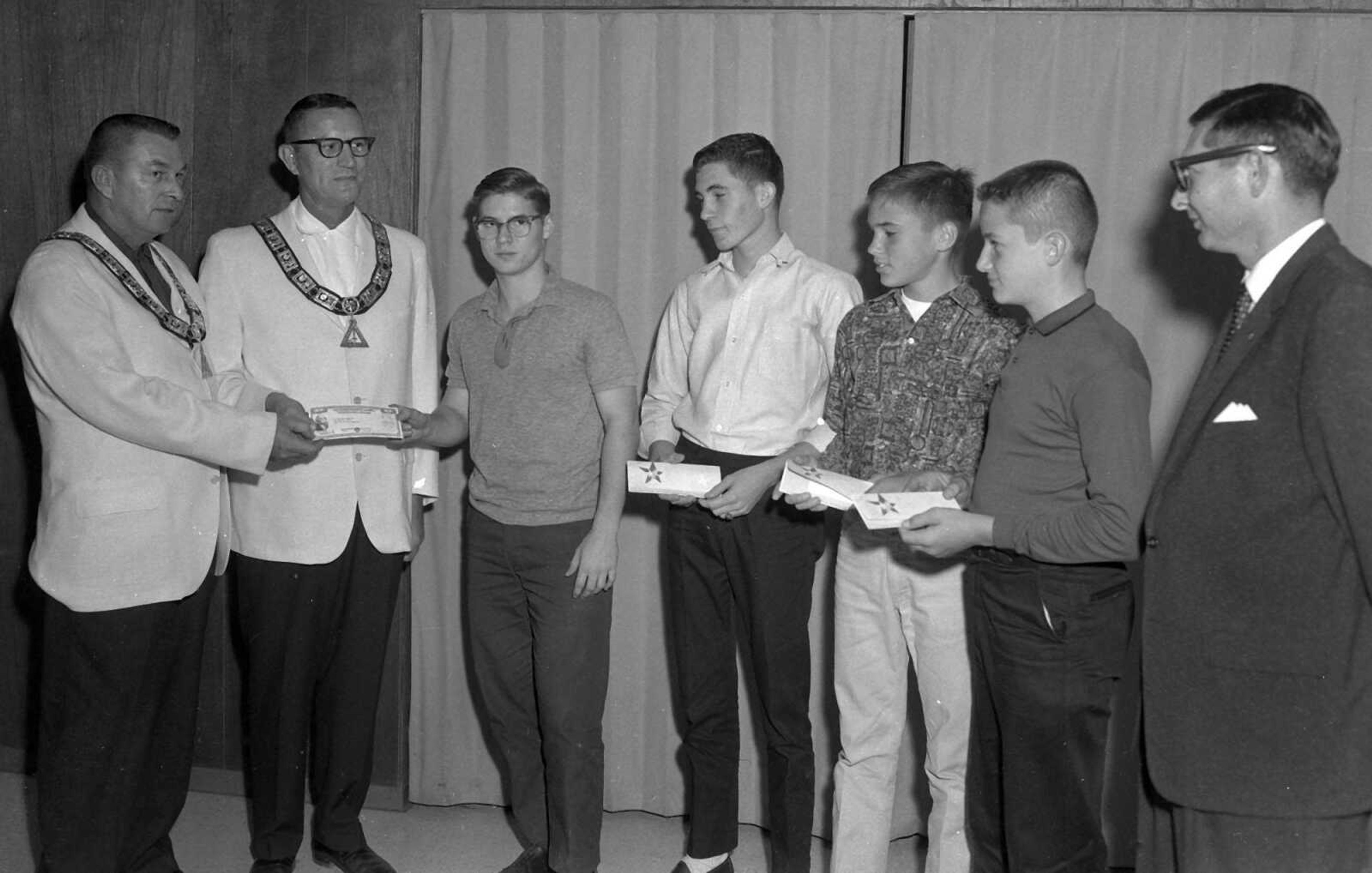 This photo appears to show members of a masonic order distributing U.S. Savings Bonds to unidentified youths. Bill Stone wrote: "This photo may have something to do with DeMolay. My cousin, Bob Stone, is four from the left."