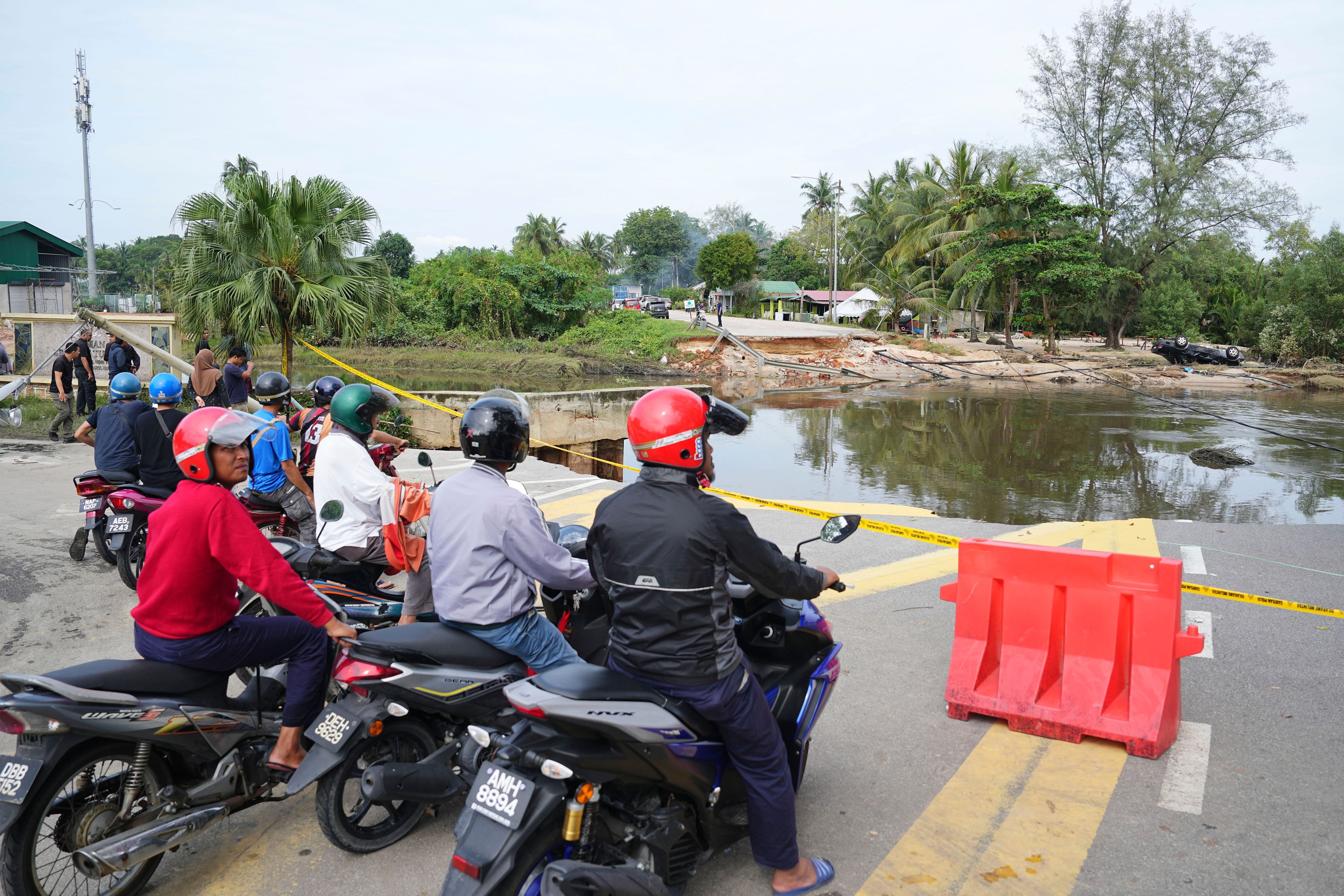 Motorists survey a road damaged by a flood in Tumpat, on the outskirts of Kota Bahru in Kelantan state on the east coast of Malaysia, Tuesday, Dec. 3, 2024. (AP Photo/Vincent Thian)