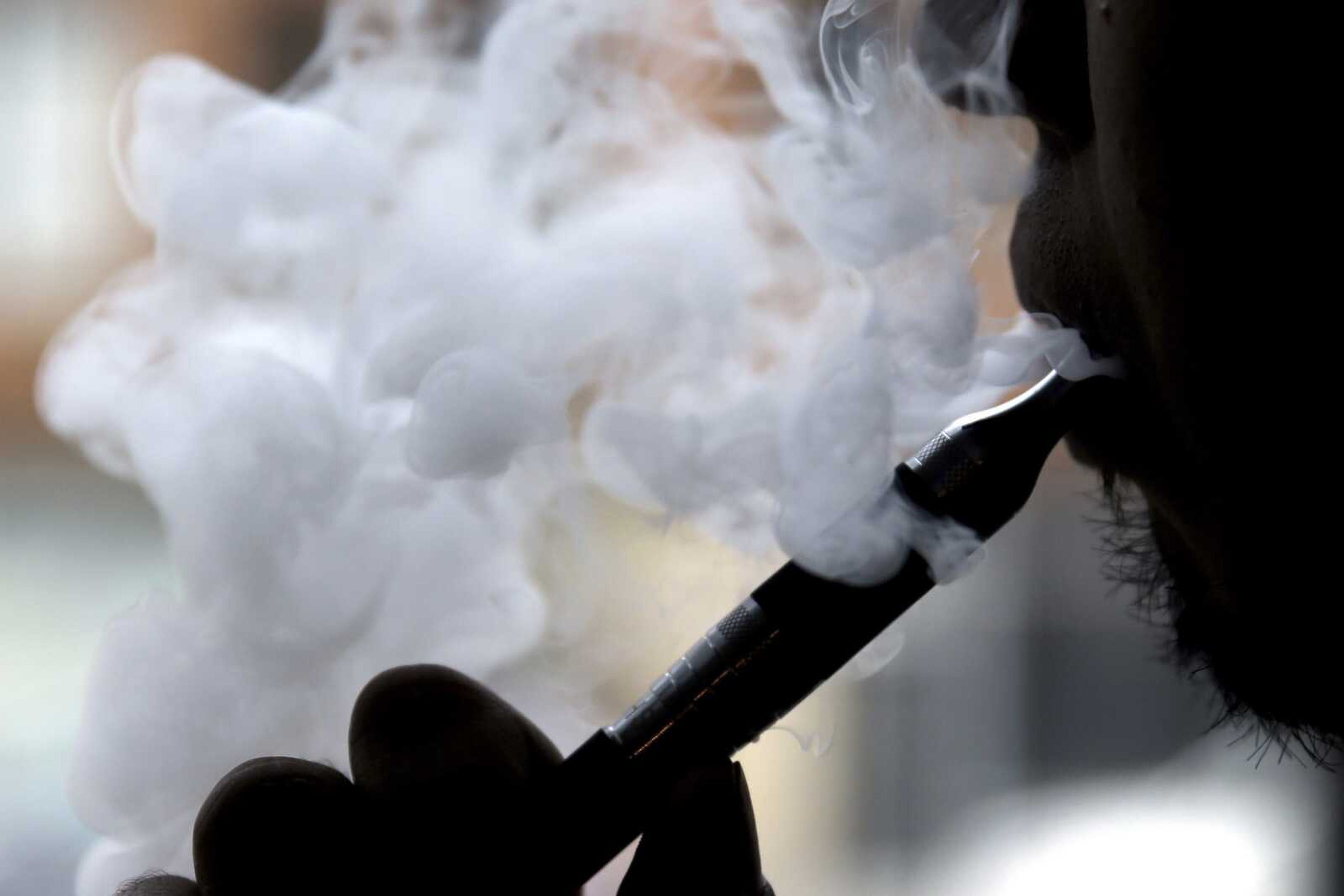 A man smokes an electronic cigarette April 23, 2014, in Chicago. On Friday, the Centers for Disease Control and Prevention said they are investigating more cases of a breathing illness associated with vaping. The root cause remains unclear, but officials said Friday many reports involve marijuana vaping.