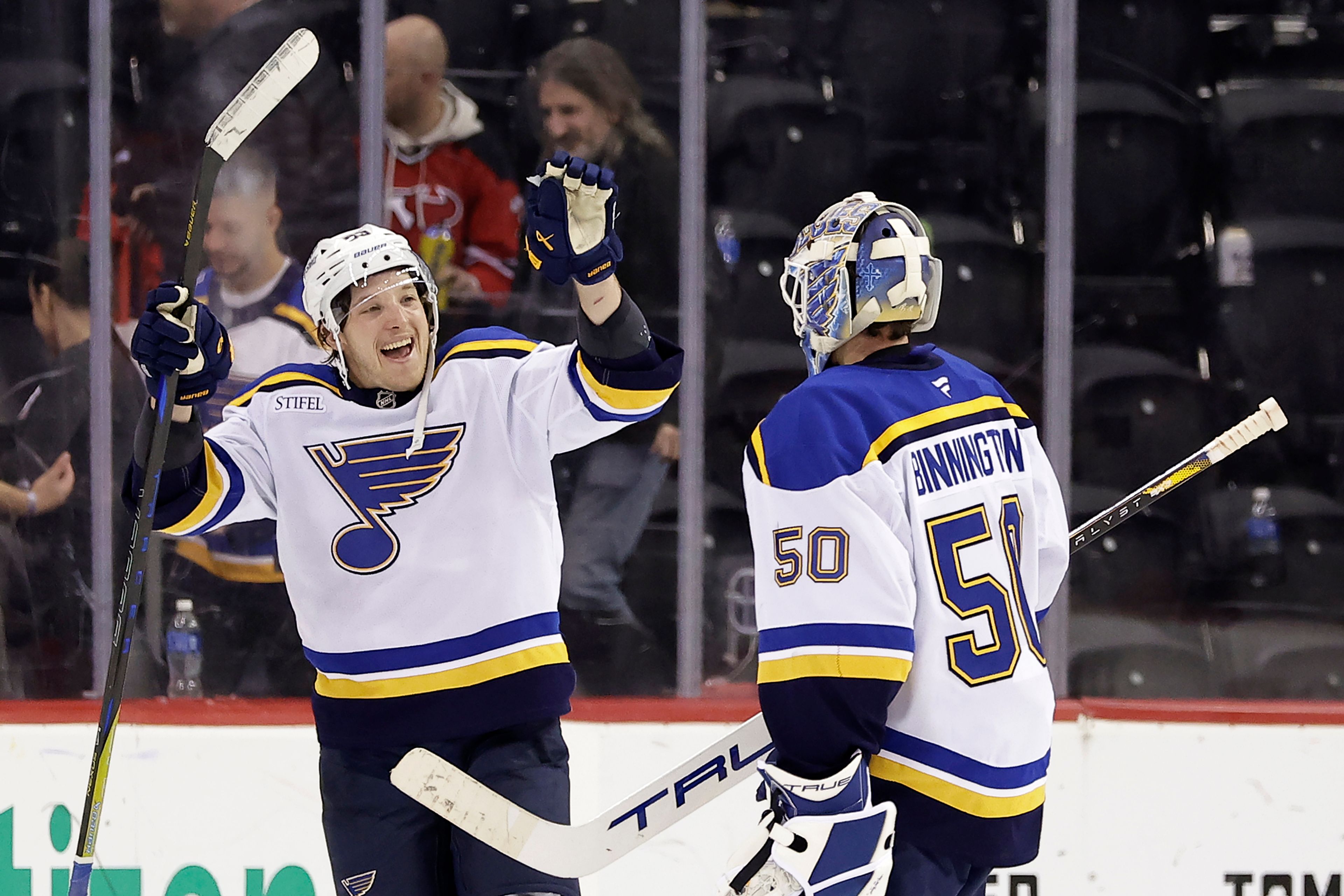 St. Louis Blues left wing Jake Neighbours reacts towards goaltender Jordan Binnington (50) after beating the New Jersey Devils 3-0 in an NHL hockey game Wednesday, Nov. 27, 2024, in Newark, N.J. St. (AP Photo/Adam Hunger)