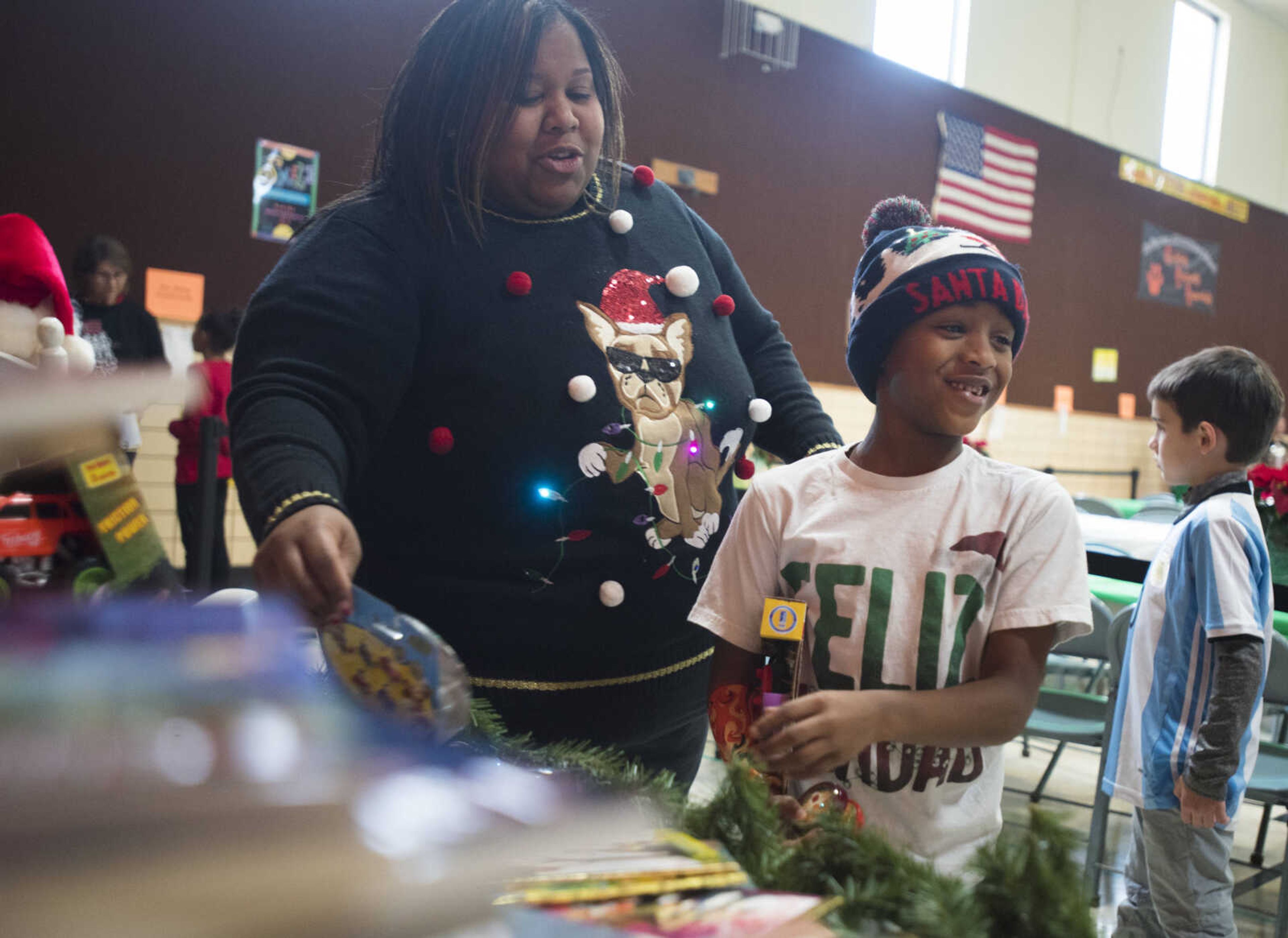 Candace Grant helps her son, Robert, 8, choose a toy during a free lunch hosted by Student Santas on Dec. 25, 2017, at Jefferson Elementary School in Cape Girardeau.