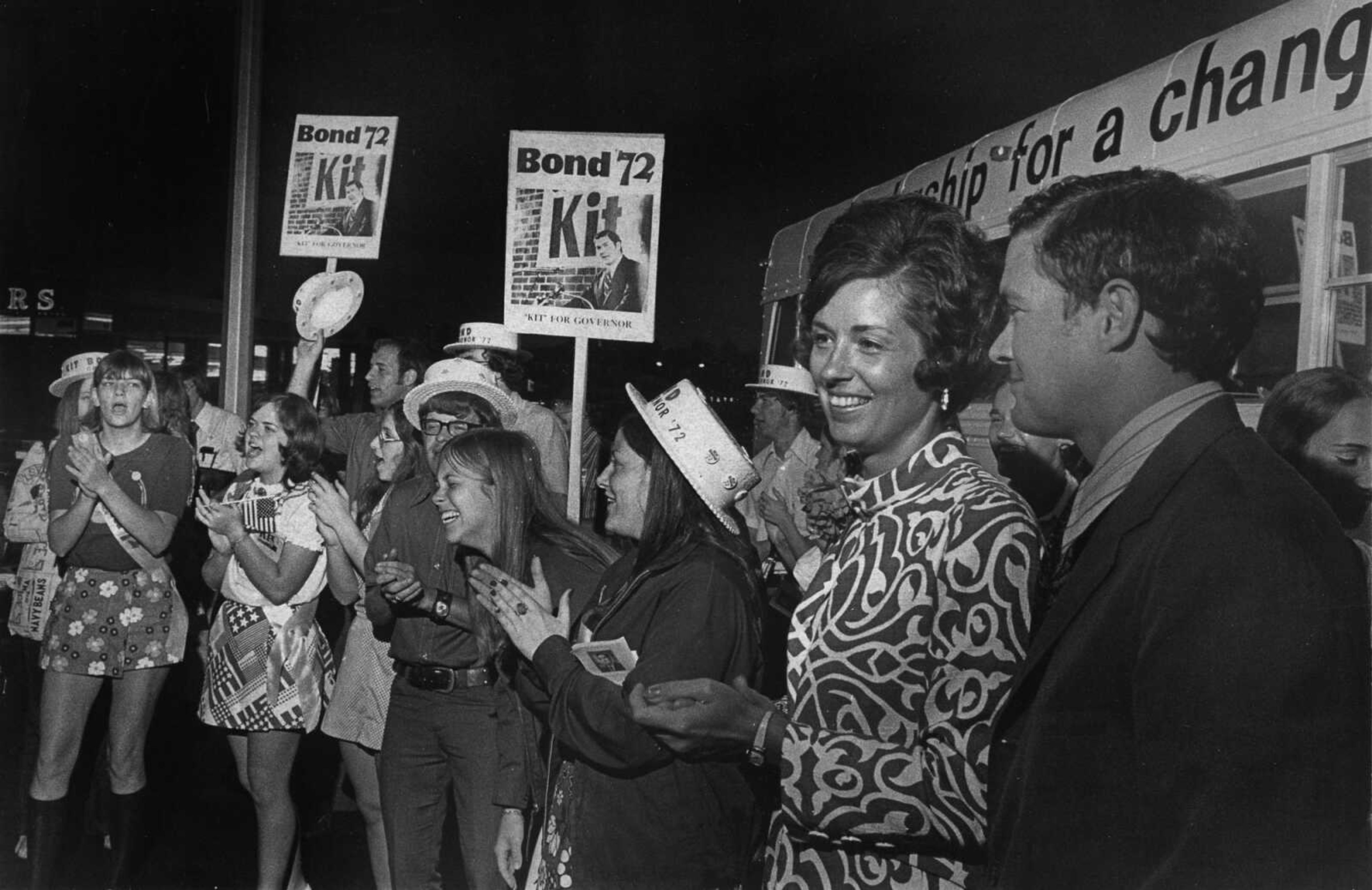 State Auditor Christopher  "Kit" Bond, right, and his wife Carolyn are surrounded by young supporters as he campaigns for the Republican nomination for governor at Capaha Park. (May 30, 1972)