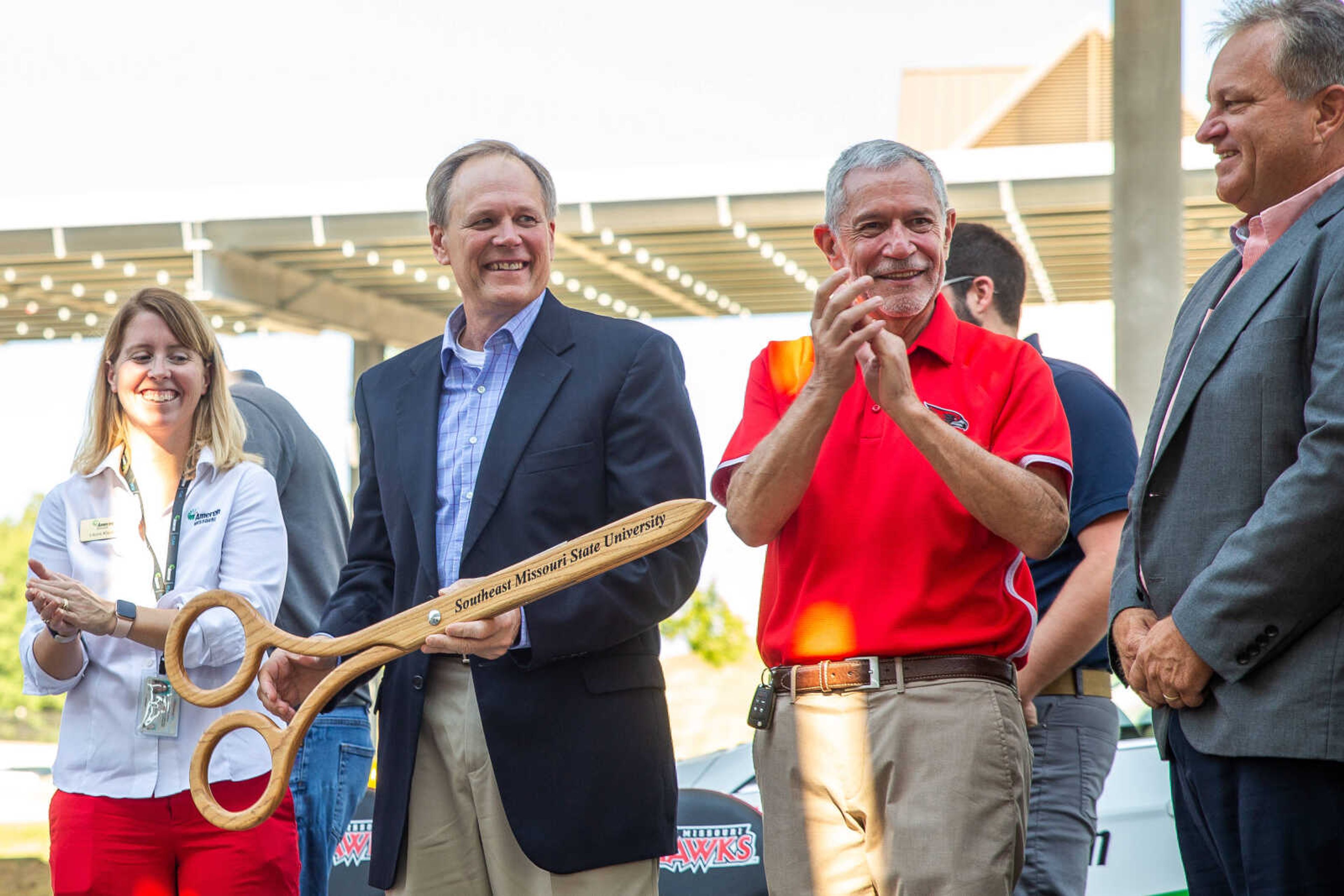 (from left) Ameren Regional Account Executive Laura Klipfel, Ameren Missouri Chairman and President Mark Birk and SEMO University President Dr. Carlos Vargas smile together after cutting a ceremonial ribbon to mark the official completion of a canopy of solar panels that cover the parking lots in front of the Show Me Center on Aug. 25.