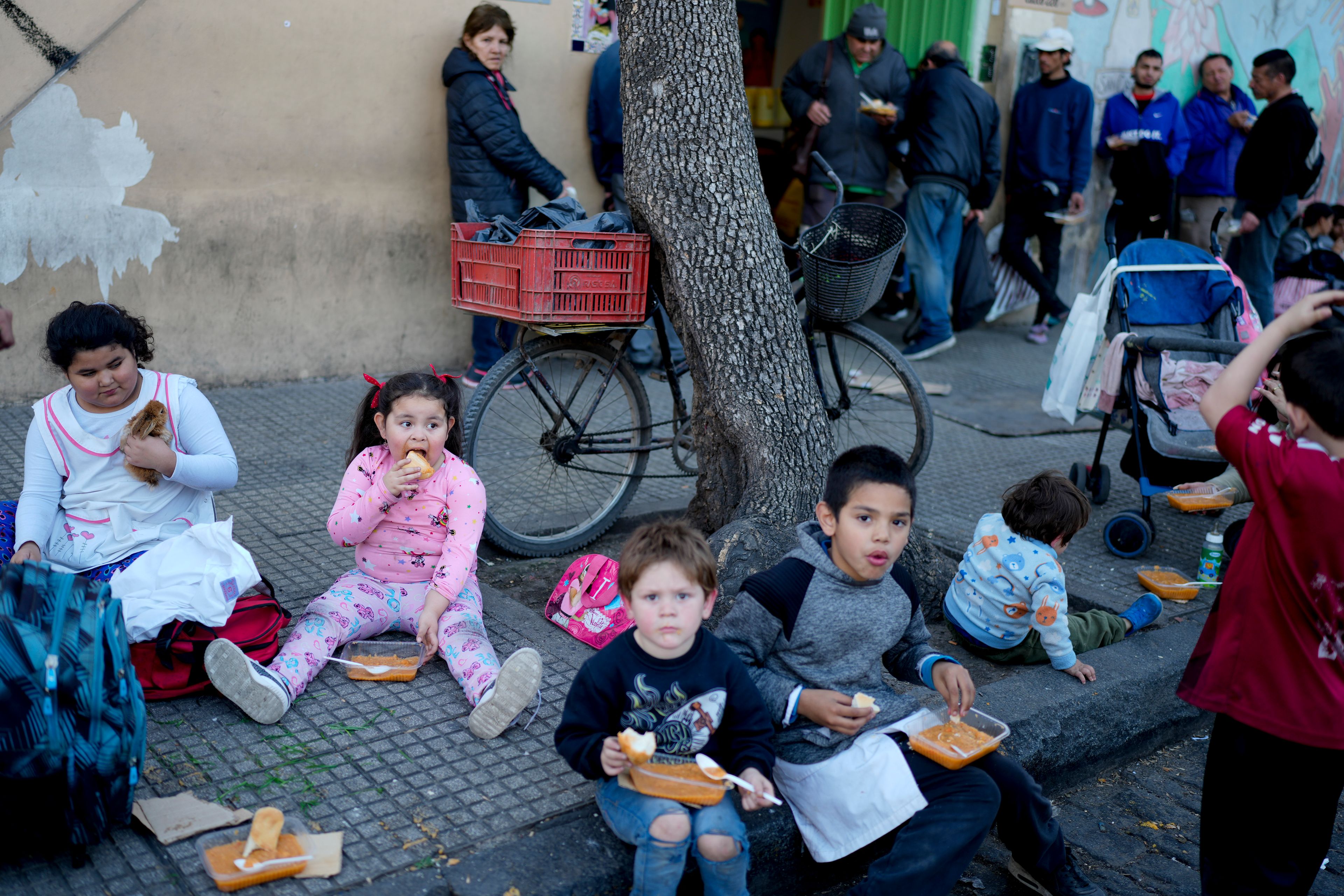 Children eat a free, cooked meal outside a soup kitchen on the outskirts of Buenos Aires, Argentina, Sept. 12, 2024. (AP Photo/Natacha Pisarenko)