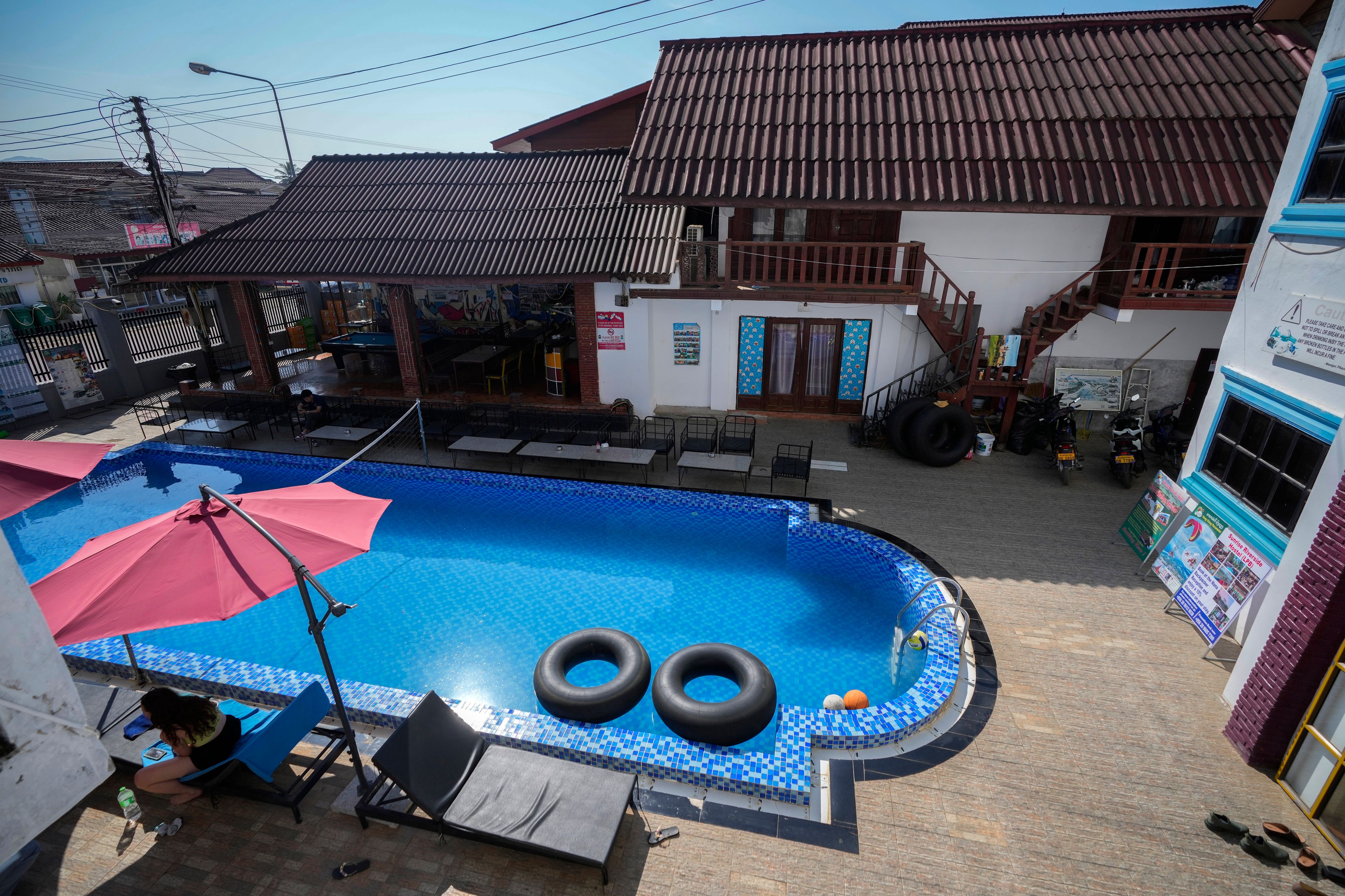 A foreign tourist rests near a swimming pool at Nana Backpackers hostel in Vang Vieng, Laos, Friday, Nov. 22, 2024. (AP Photo/Anupam Nath)