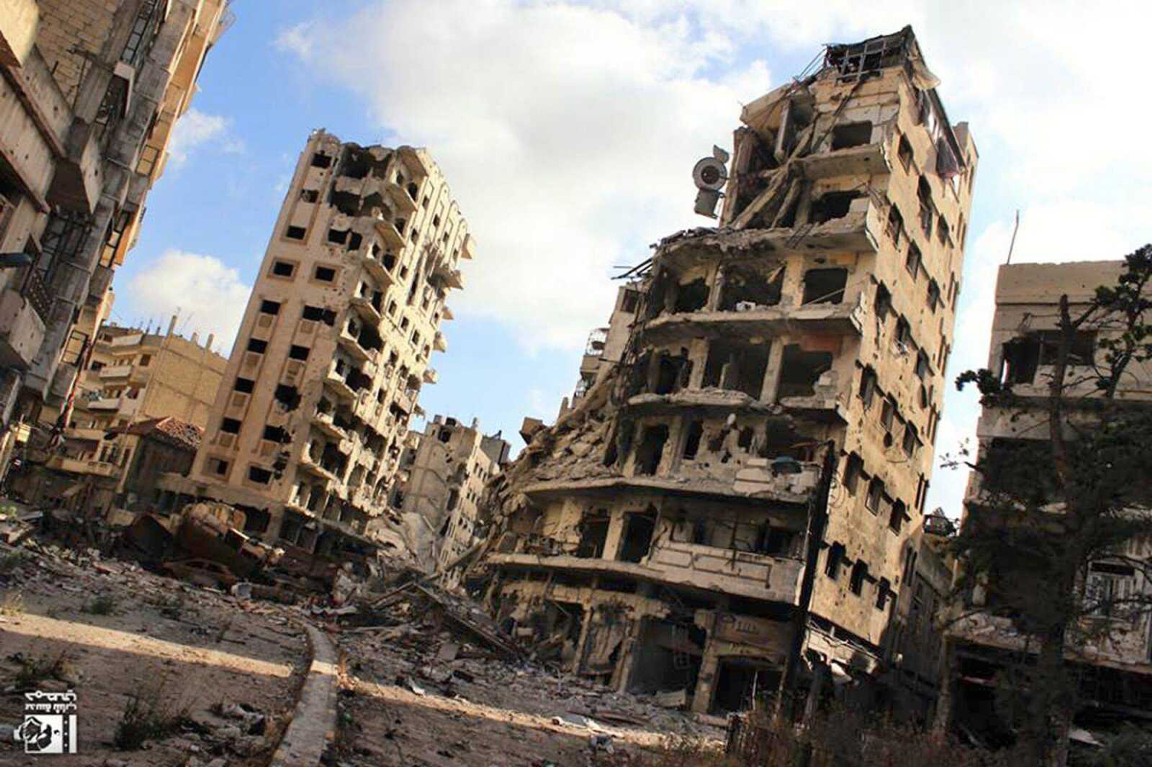 Buildings show damage by Syrian government air strikes and shelling in the Jouret al-Chiyah neighborhood of Homs, Syria. (Lens Young Homsi ~ Associated Press)