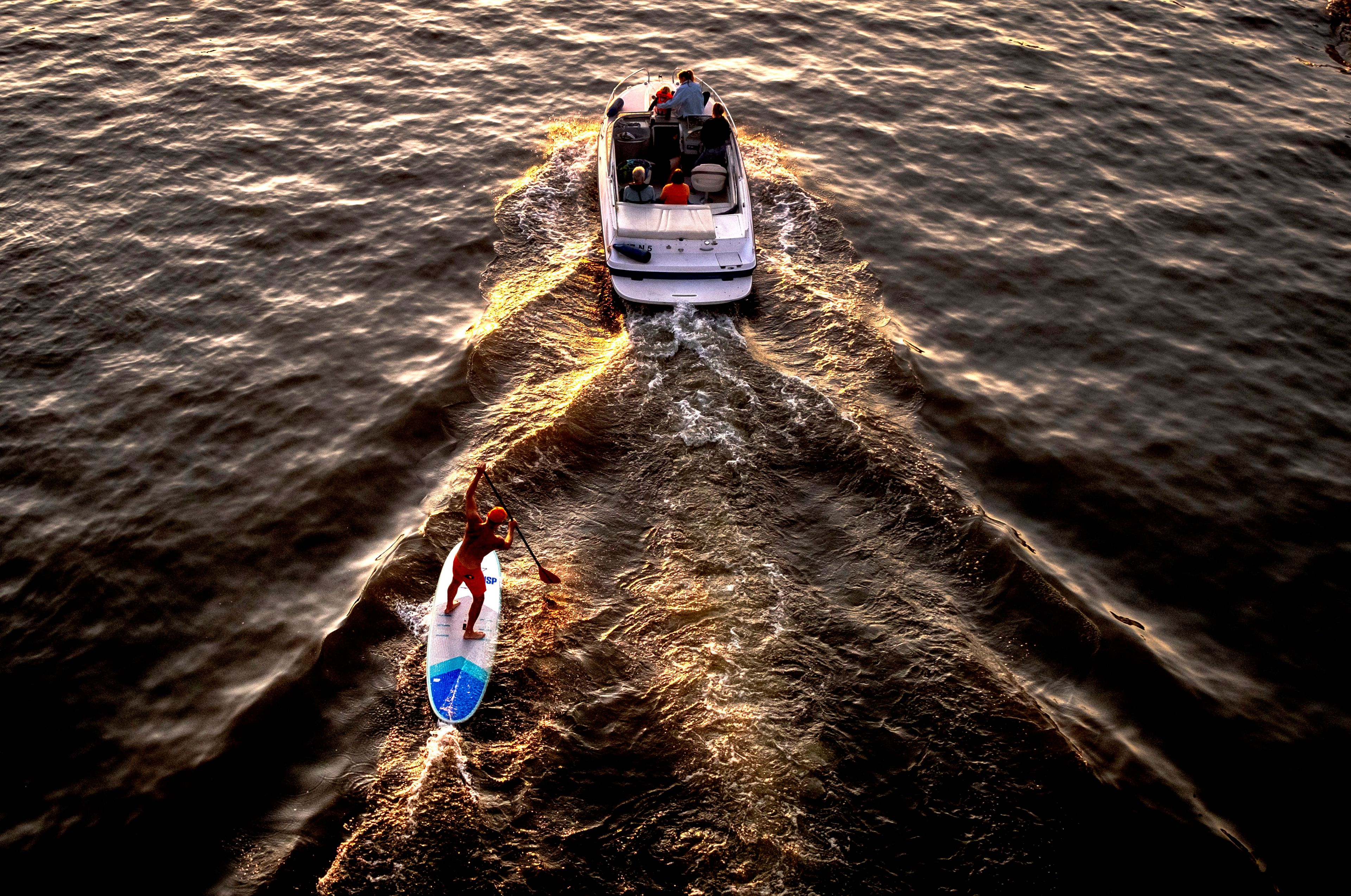 A standup paddler follows the wake of a motor boat on the river Main in Frankfurt, Germany, Friday, Sept. 20, 2024. (AP Photo/Michael Probst)