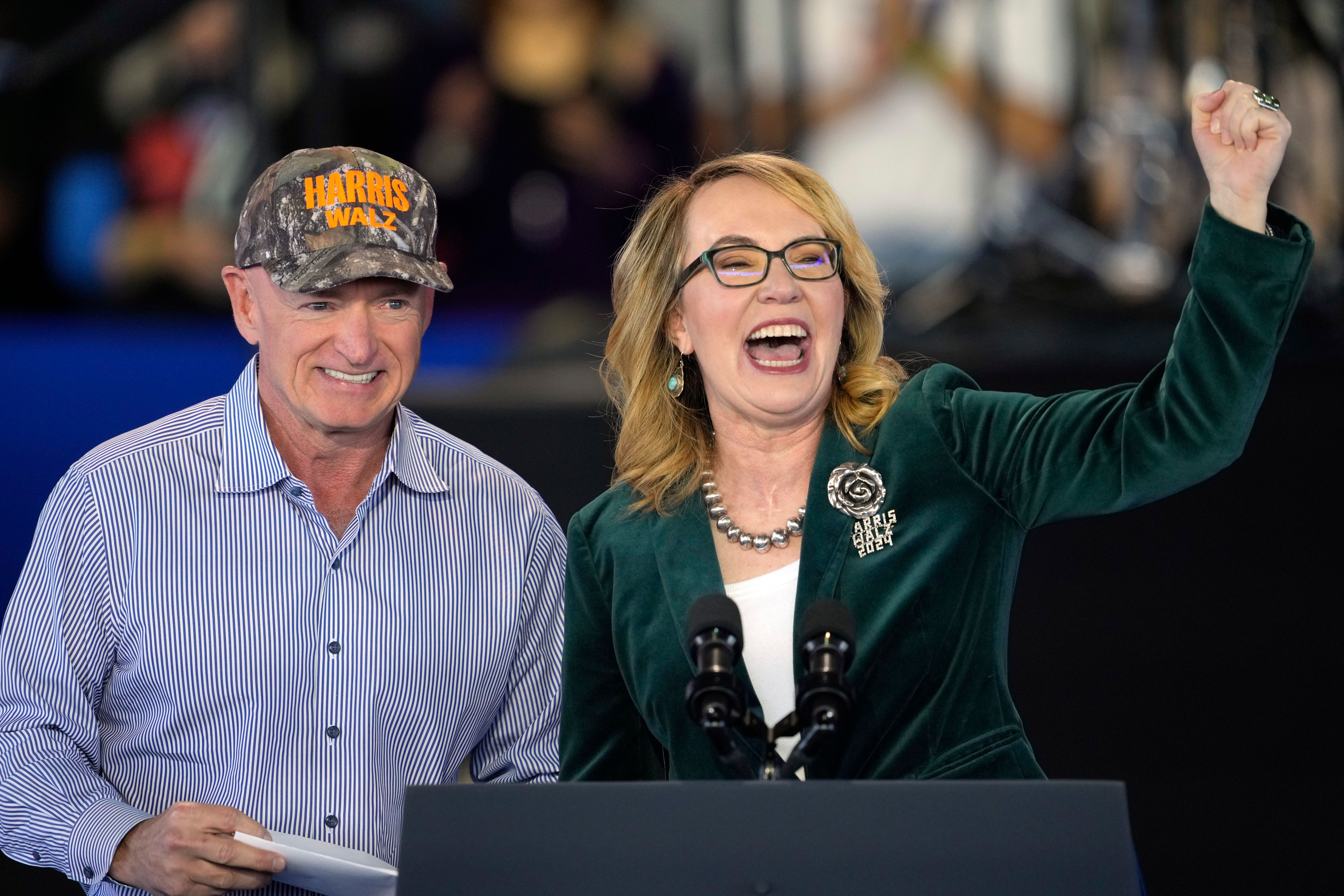 Former Arizona democratic Rep. Gabby Giffords speaks as her husband Sen. Mark Kelly, D-Ariz., looks on at a campaign event for Democratic presidential nominee Vice President Kamala Harris at Talking Stick Resort Amphitheatre, Thursday, Oct. 31, 2024, in Phoenix. (AP Photo/Matt York)