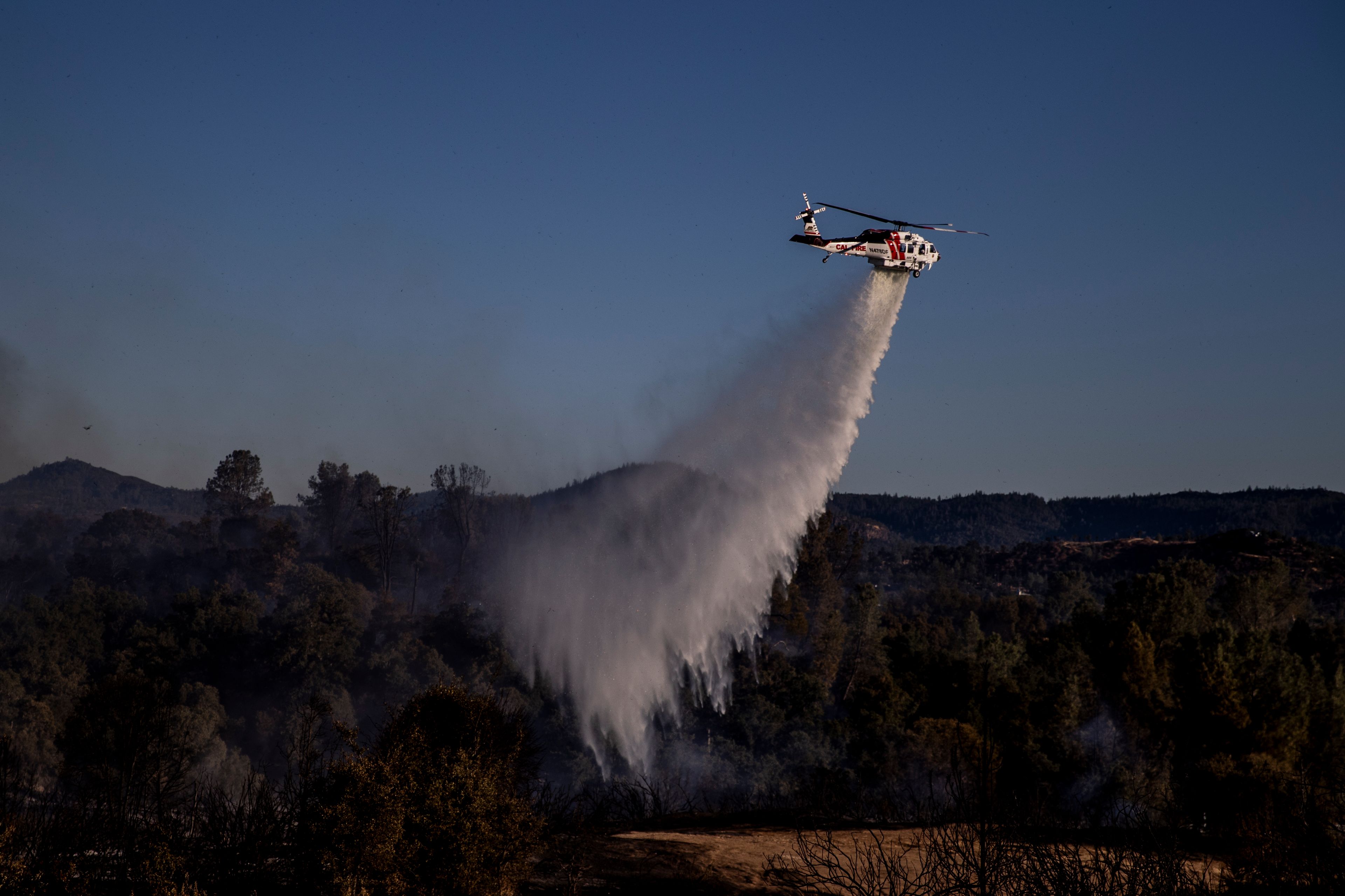 A Cal Fire Sikorsky S70i Firehawk helicopter performs a water drop on a hot spot during the Boyles fire in Clearlake, Calif., Sunday, Sept. 8, 2024. (Stephen Lam/San Francisco Chronicle via AP)