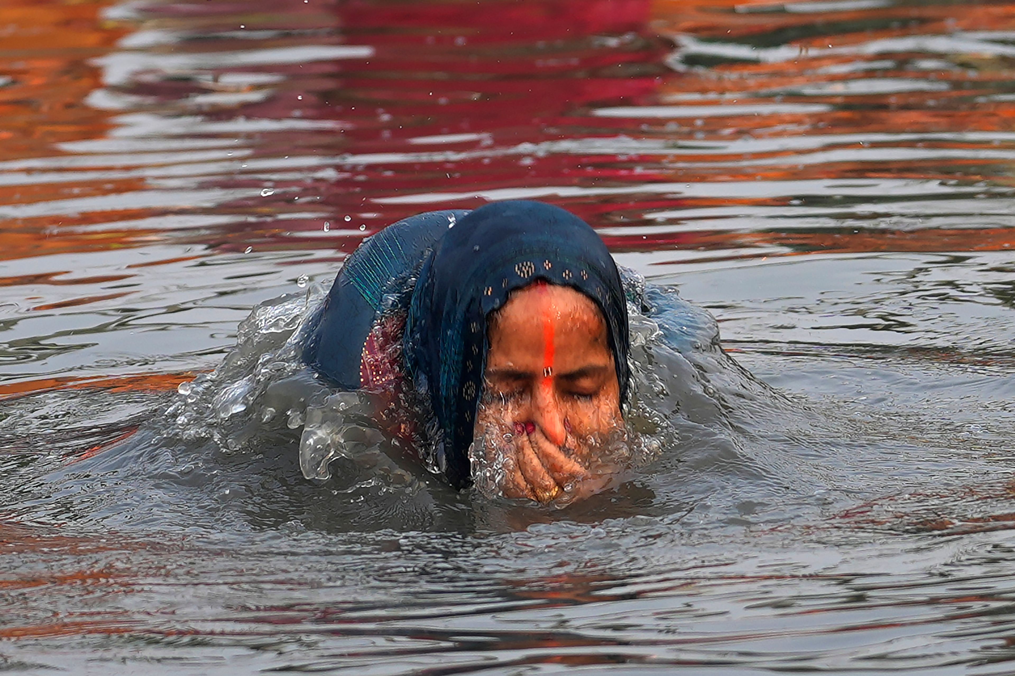 A devotee takes a dip in the river Yamuna before offering prayers to the sun god during Chhath festival in Noida, near New Delhi, India, Thursday, Nov. 7, 2024. (AP Photo/Manish Swarup)