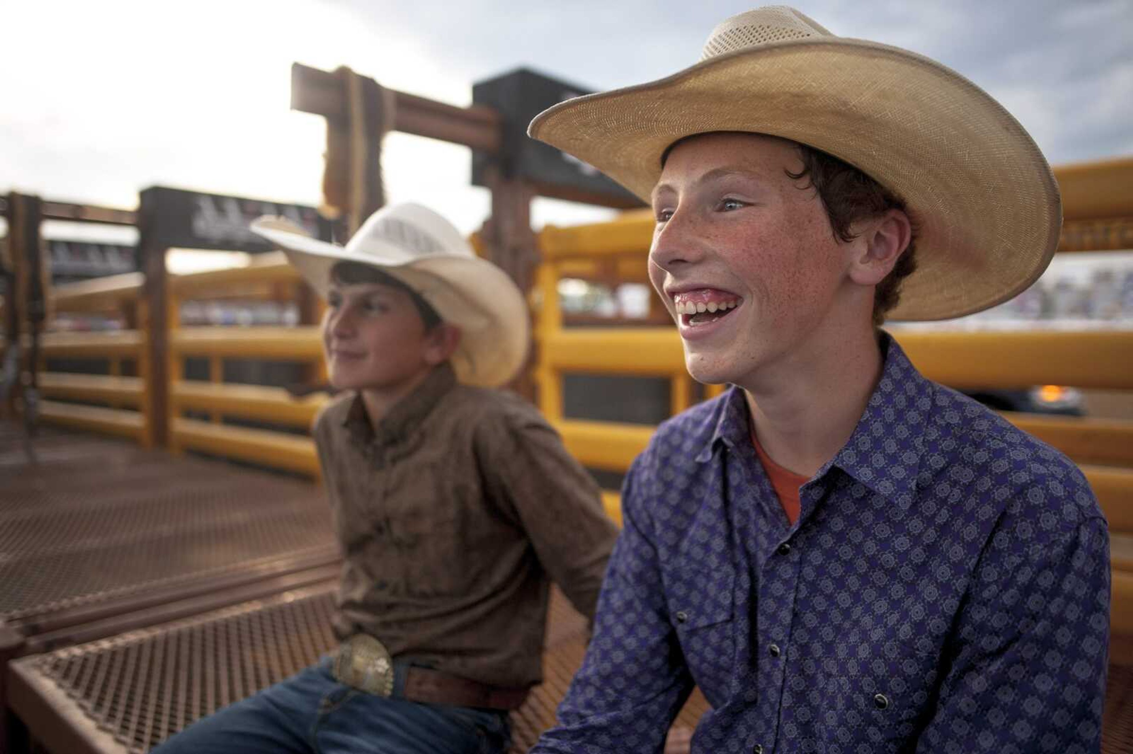 Trell Amoss, 13, right, laughs while sitting with Cade Smith, 13, as they watch cowboys prepare to perform during the Sikeston Jaycee Bootheel Rodeo Wednesday in Sikeston. Smith, from Iowa, and Amoss, originally from Malden, Missouri, travel with the rodeo around the country. Both said they intend to ride in the rodeo as they get older, but Amoss said his long-term intention is to become an equine veterinarian.