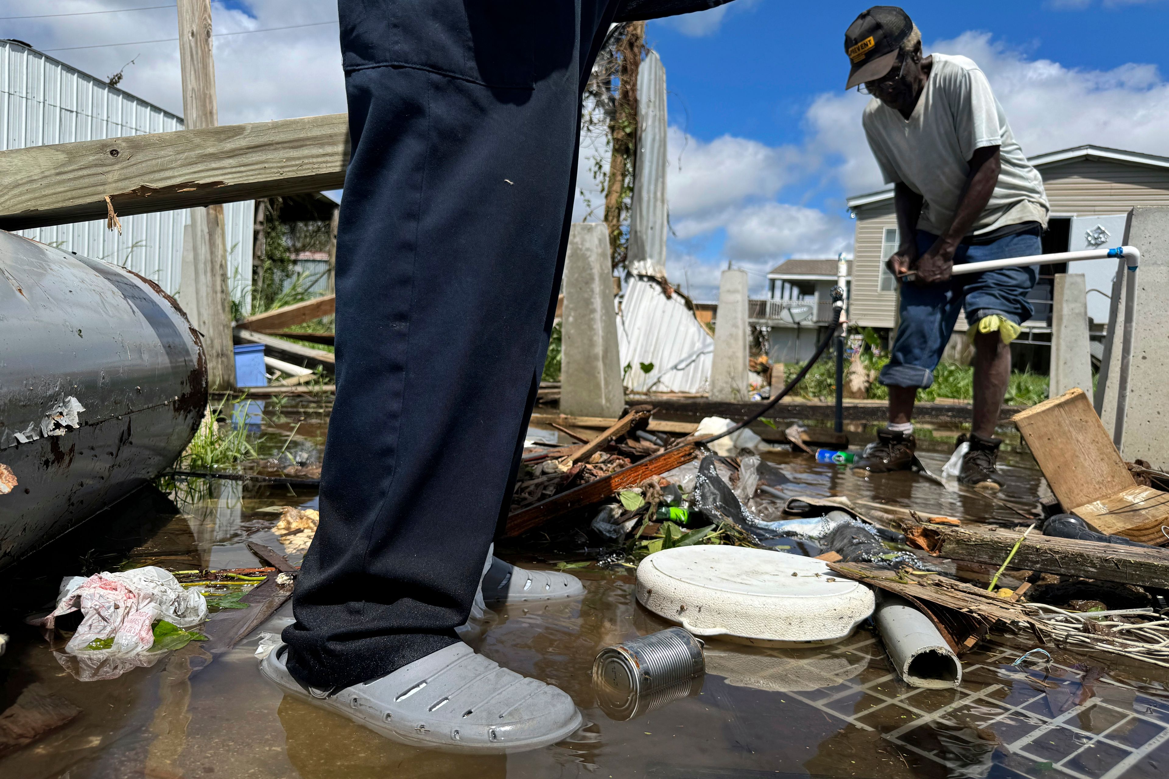 Brothers Wilson Garner, 73, left, and Carter Caldwell, 69, try to fix a broken water pipe, Thursday, Sept. 12, 2024, in Ashland, La., in the aftermath of Hurricane Francine. (AP Photo/Jack Brook)