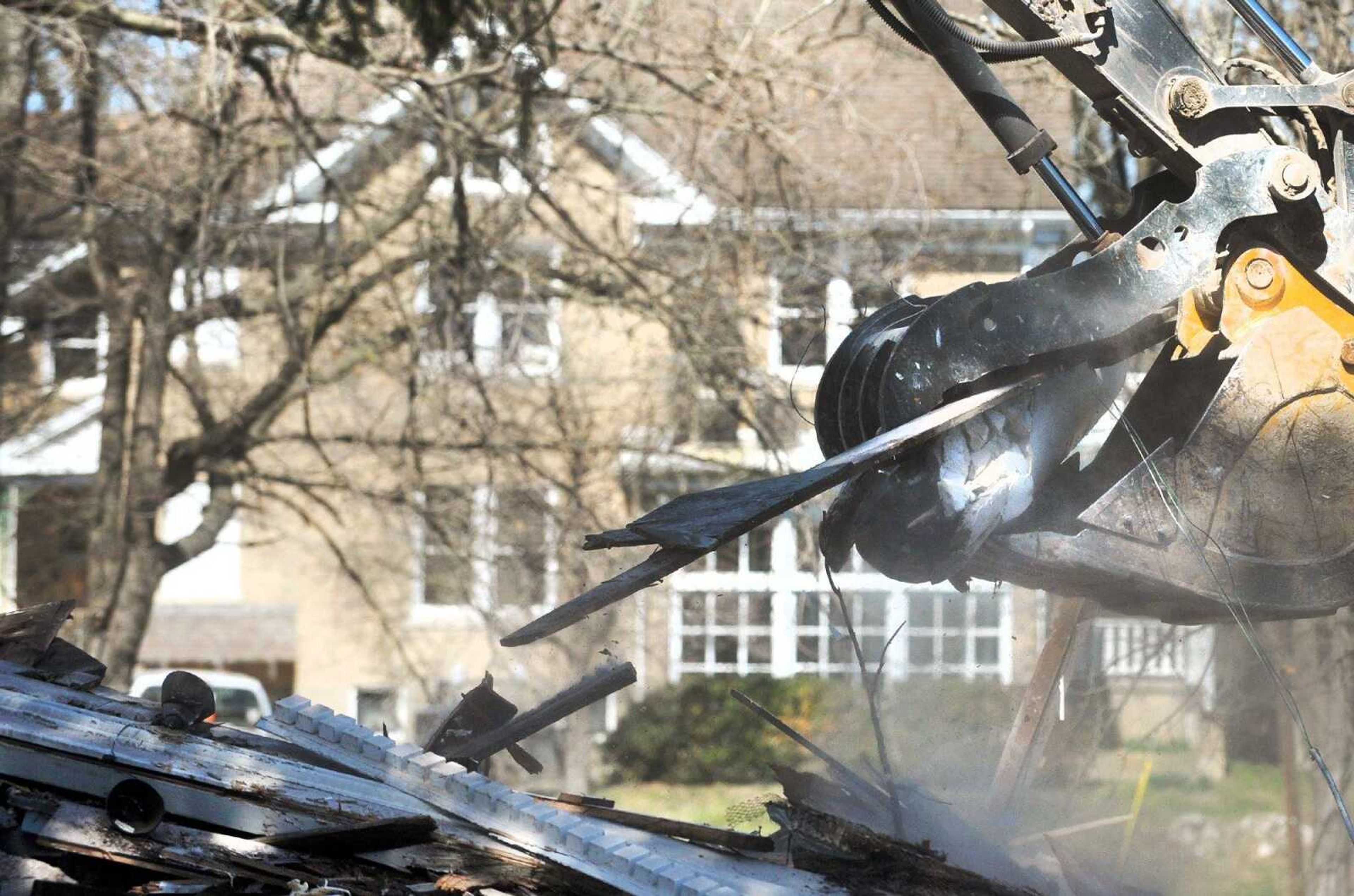 The Shivelbine House is seen in the background Tuesday as an excavator removes rubble from where Greystone Estate stood off Sprigg Street. The estate, built in 1921, was used for years by Southeast Missouri State University fraternities. Shivelbine also is slated to be demolished for a housing project for Greek organizations. (Laura Simon)