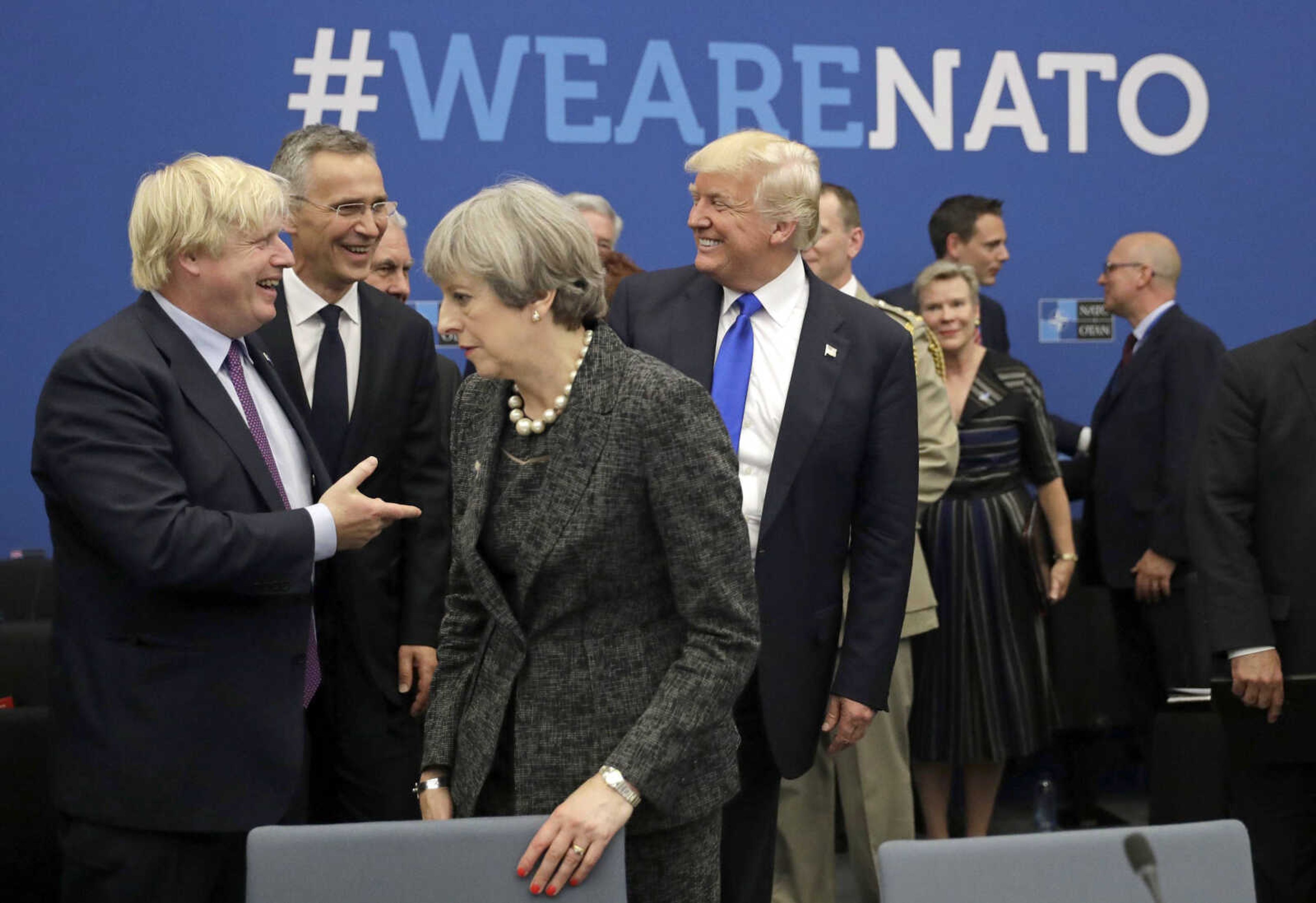 U.S. President Donald Trump jokes with British Foreign Minister Boris Johnson as British Prime Minister Theresa May walks past May 25, 2017, during a working dinner meeting at the NATO headquarters during a NATO summit of heads of state and government in Brussels.