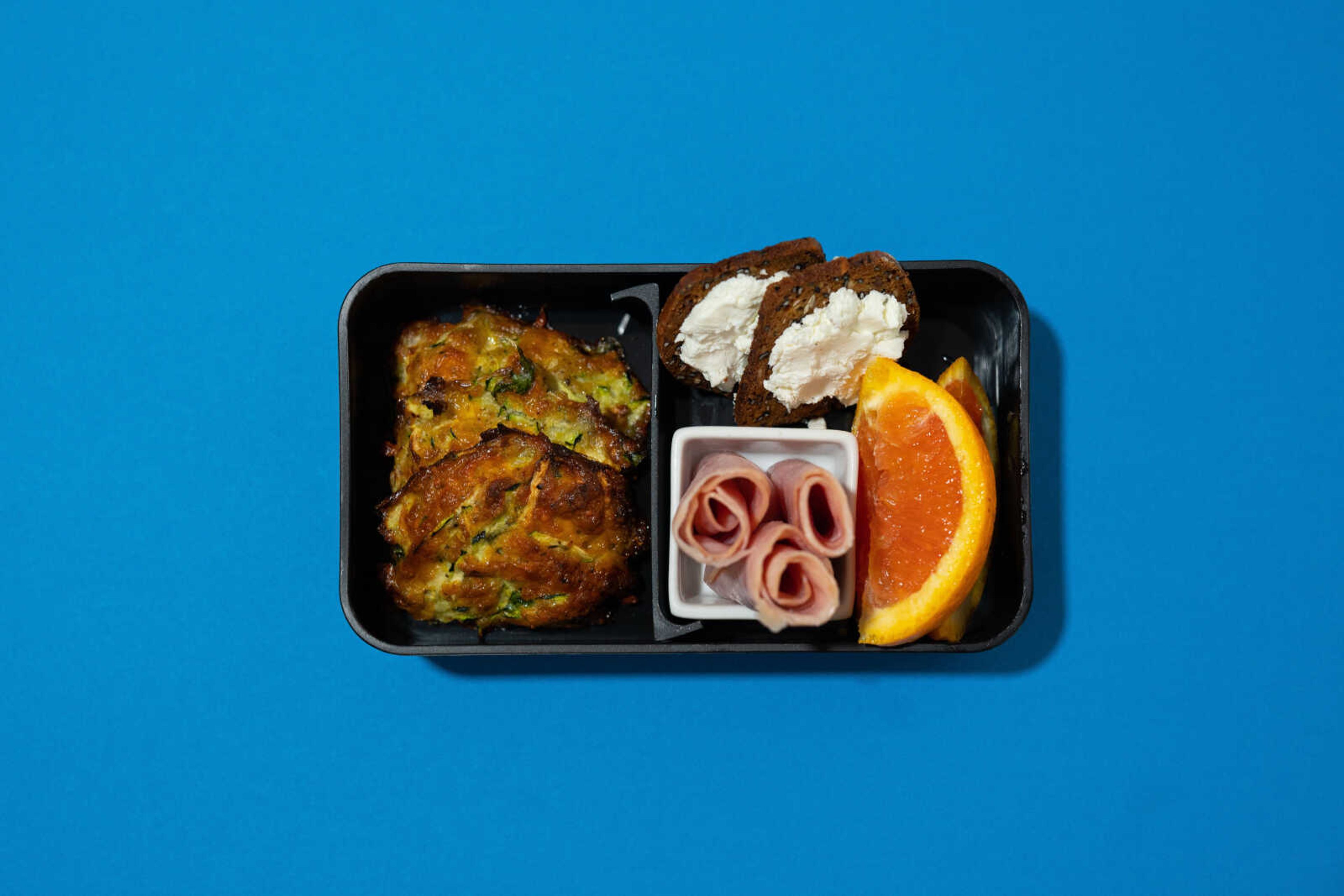 Cheesy zucchini bites, ham rolls and bread prepared by Ellen Gipson, MA, RDN, LD, are arranged in a bento box. Building meals from simple, whole foods will help ensure your body gets the micronutrients and macronutrients it needs.