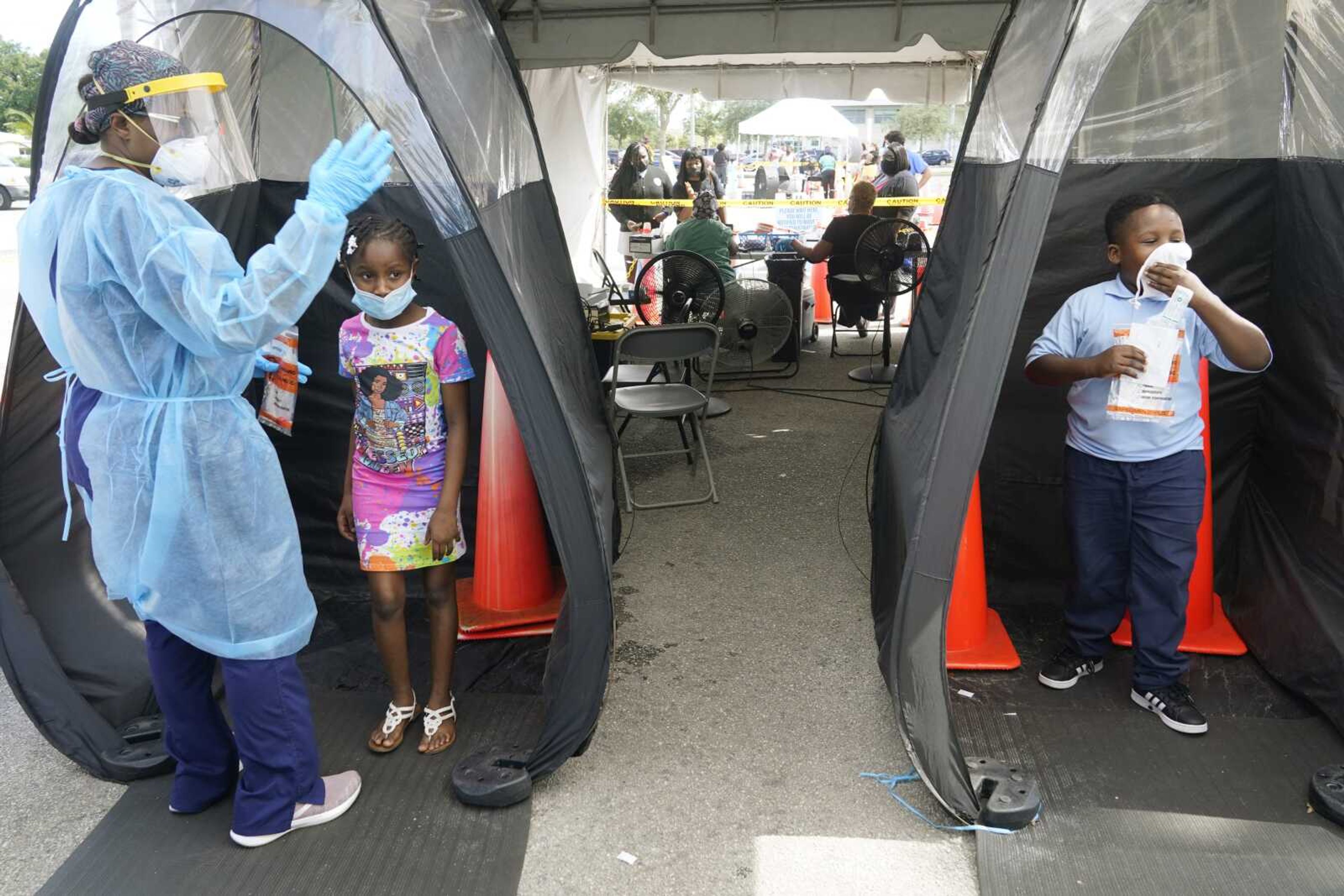 Wenderson Cerisene, 7, right, and his sister Dorah, 9, wait to get tested for COVID-19 Tuesday in North Miami, Florida. Florida schools are seeing a rise in COVID-19 cases forcing of students and teachers to quarantine.