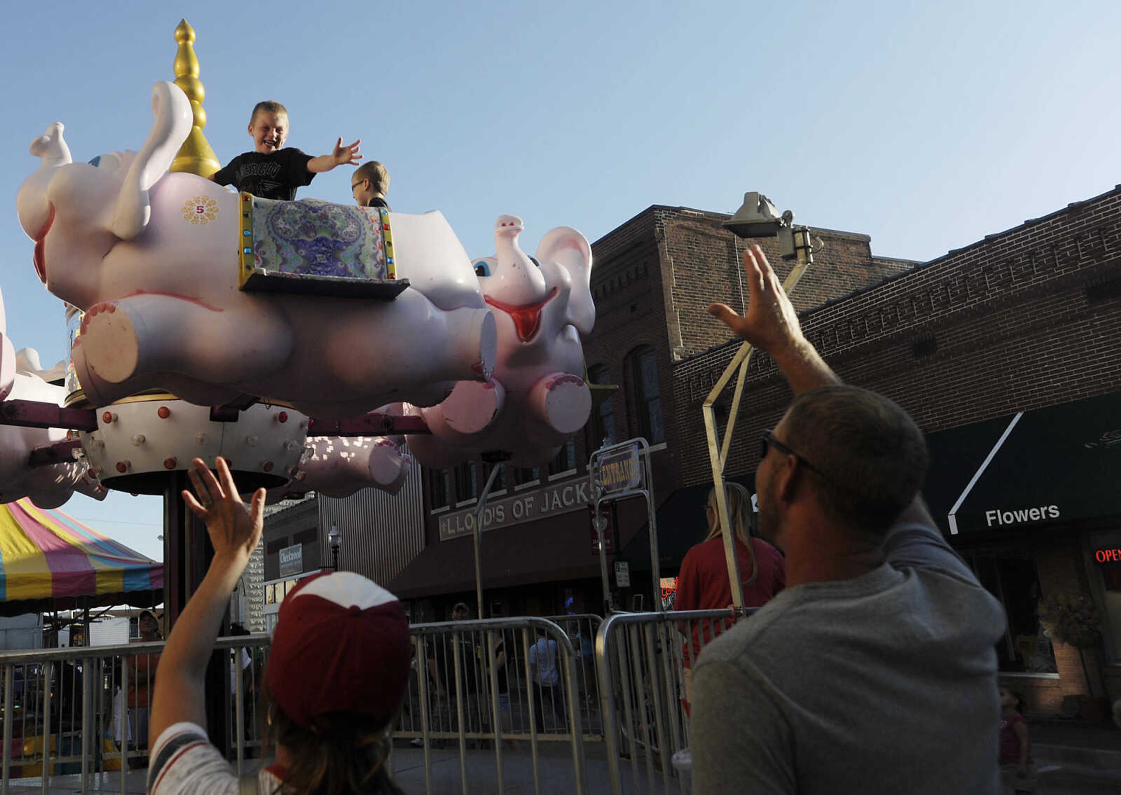 Alana, left, and Justin Borgfield, of Daisy, Mo., wave at their sons, Kaden, 6, left, and Tristen as they pass by on the pink elephant ride at the carnival during the 105th Jackson Homecomers celebration Wednesday, July 24, in Jackson, Mo.