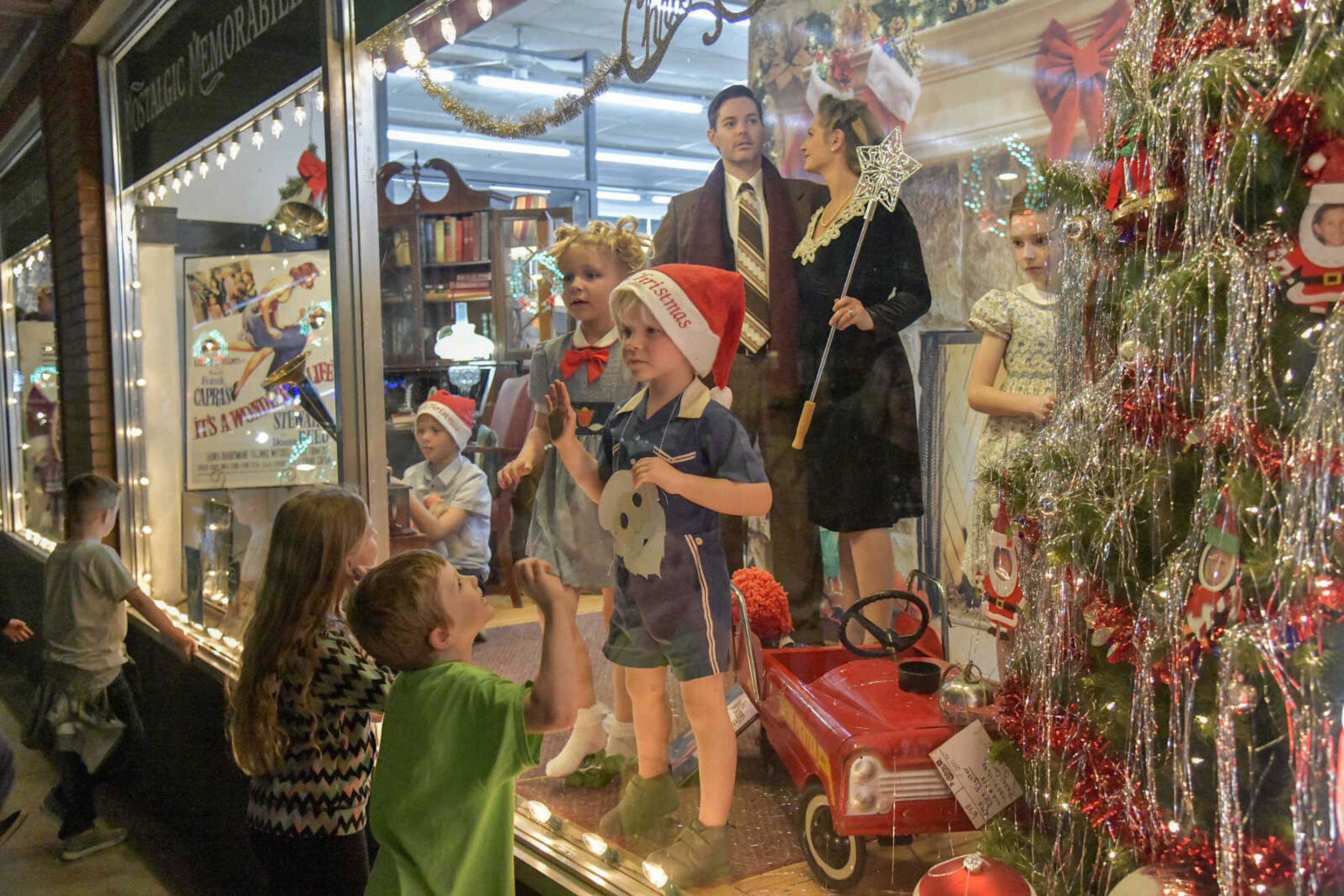 Children outside try to distract child actors inside the "It's a Wonderful Life" Christmas Window at Pastimes Antiques during the Annual Downtown Holiday Open House on Friday in Cape Girardeau.