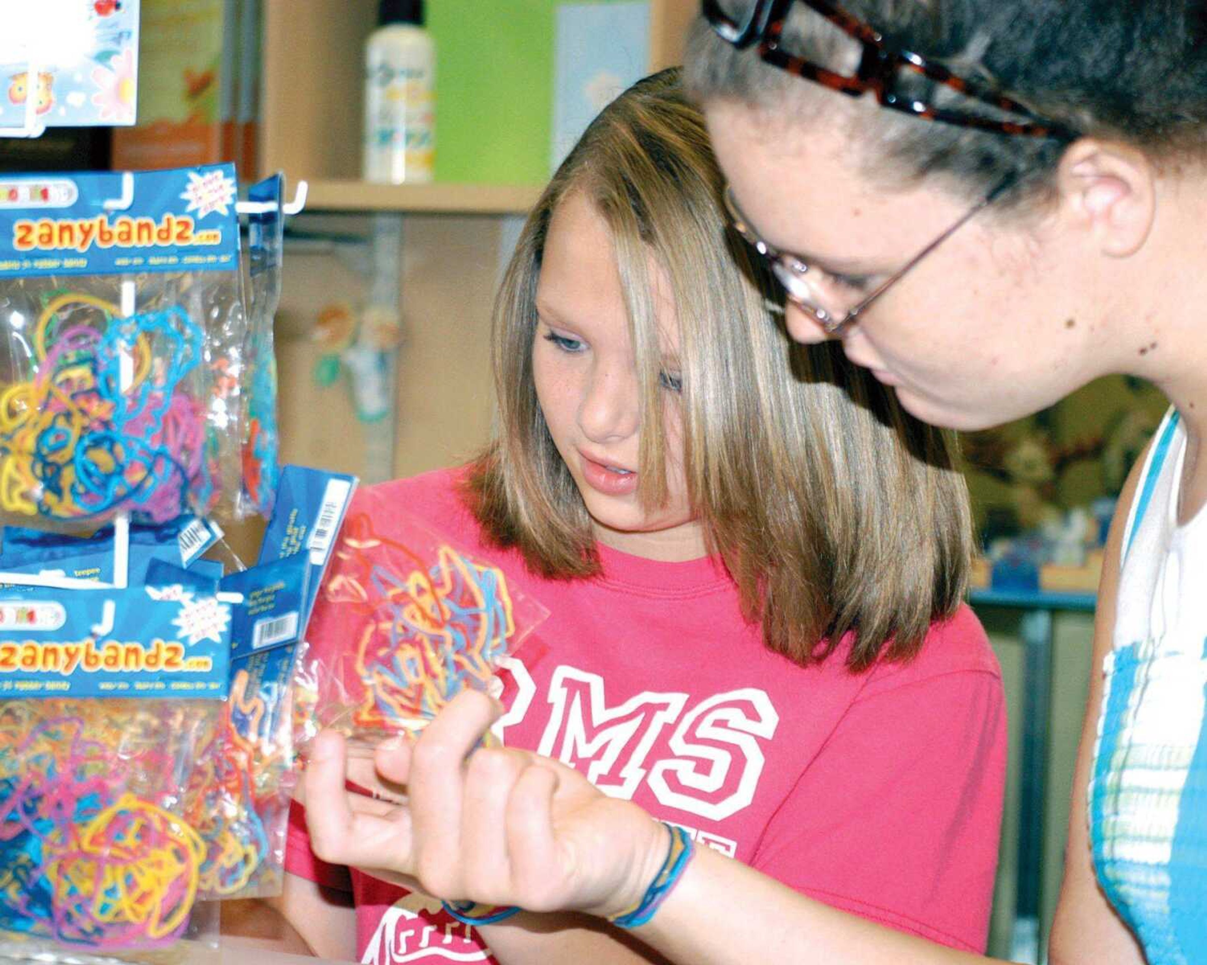 Madi Basham, 13, and Jordan Crawford, 12, of Sikeston look through Zanybandz at Carol's Hallmark in Sikeston. The brightly colored rubber bands shaped liked animals, letters, musical instruments and more are among the latest trend with children this summer. The bands transform into wavy bracelets when placed on the wrist. (LeonNa Heuring ~ Standard Democrat)