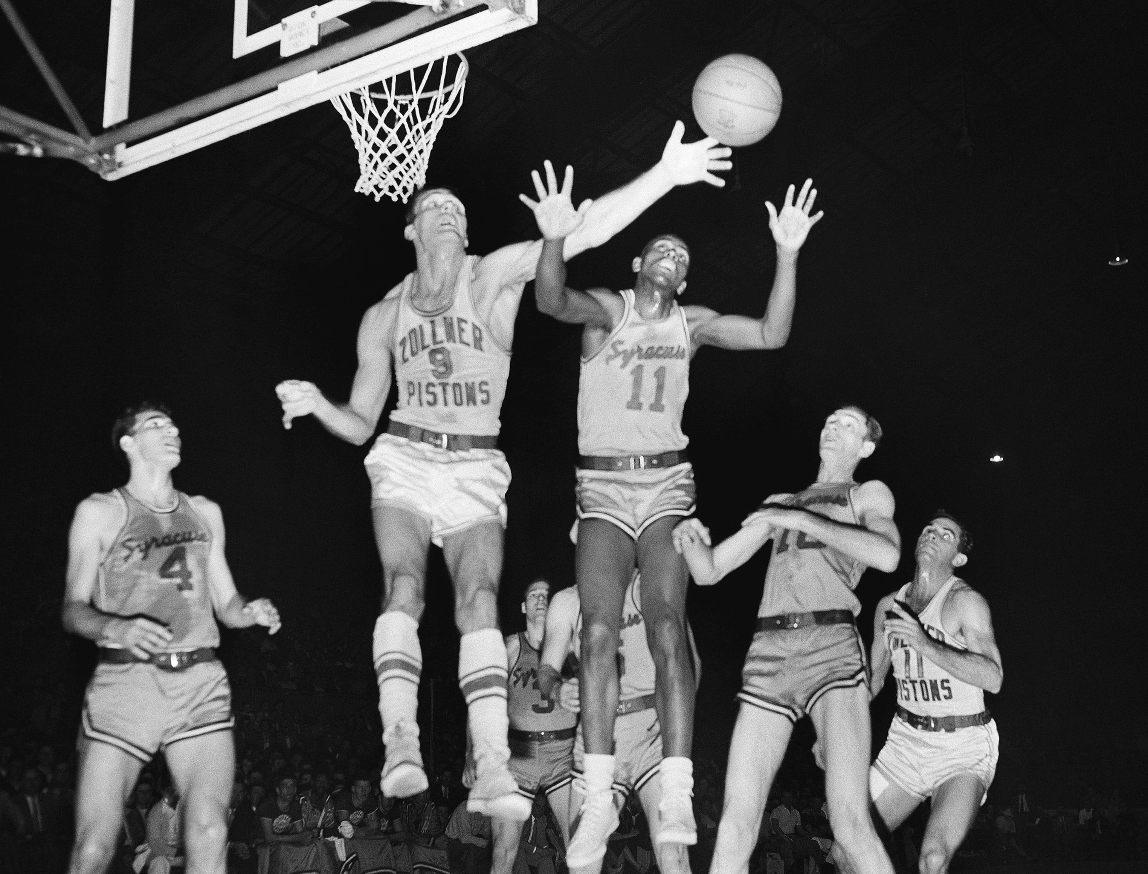 In this April 1955 file photo, Fort Wayne's Mel Hutchins (9) and Syracuse's Earl Lloyd (11) reach for the ball during an NBA basketball game in Indianapolis. Lloyd was the first black player in NBA history. 