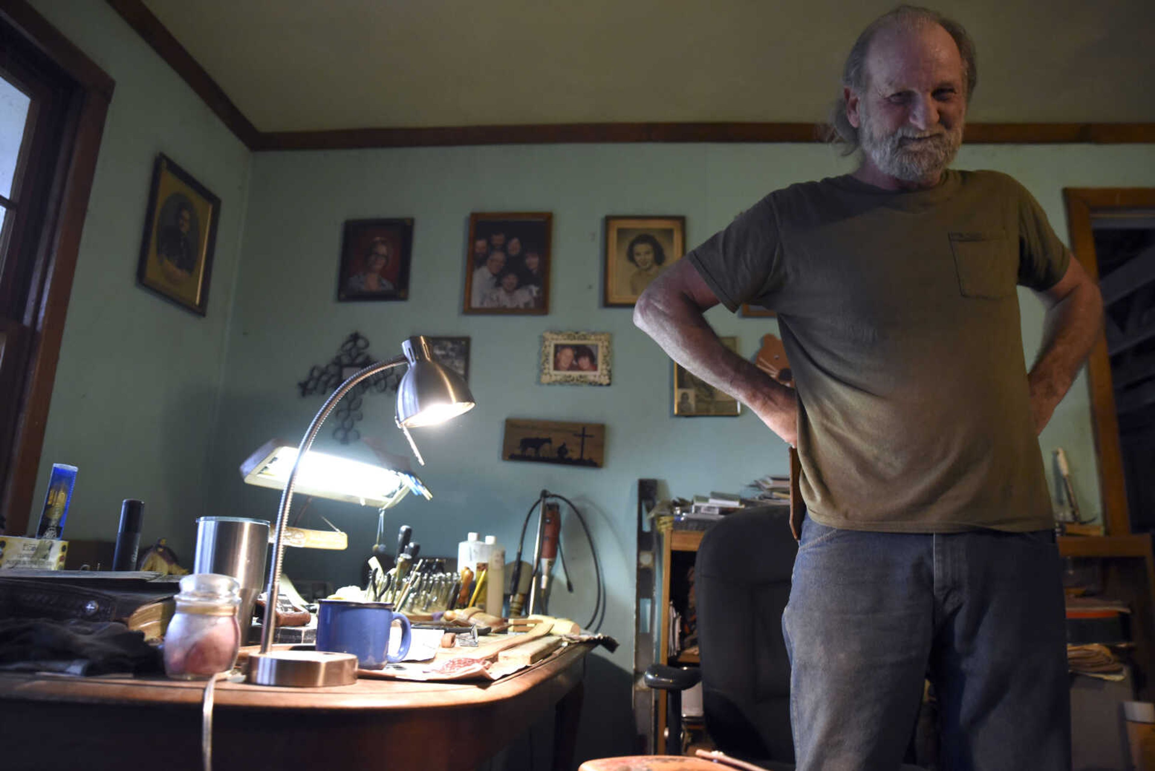 John Hedge stands by his desk used for his leather making in his home on Tuesday, March 27, 2018, in Advance.