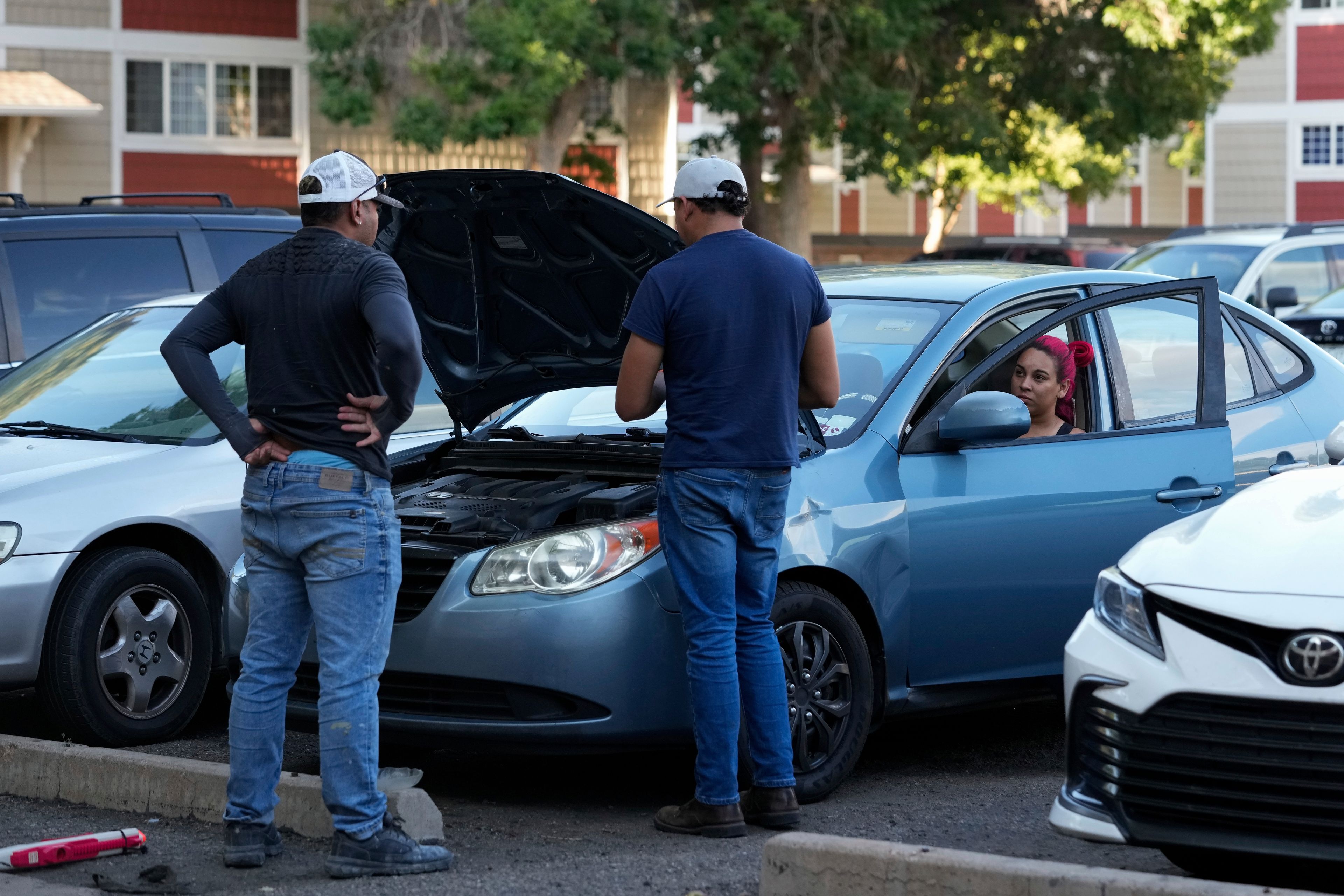 Gabriela Ramírez, right, and her boyfriend Ronexi Bocaranda, left, listen as mechanic diagnoses issues with Gabriela's car Thursday, Aug. 29, 2024, in Aurora, Colo. (AP Photo/Godofredo A. Vásquez)