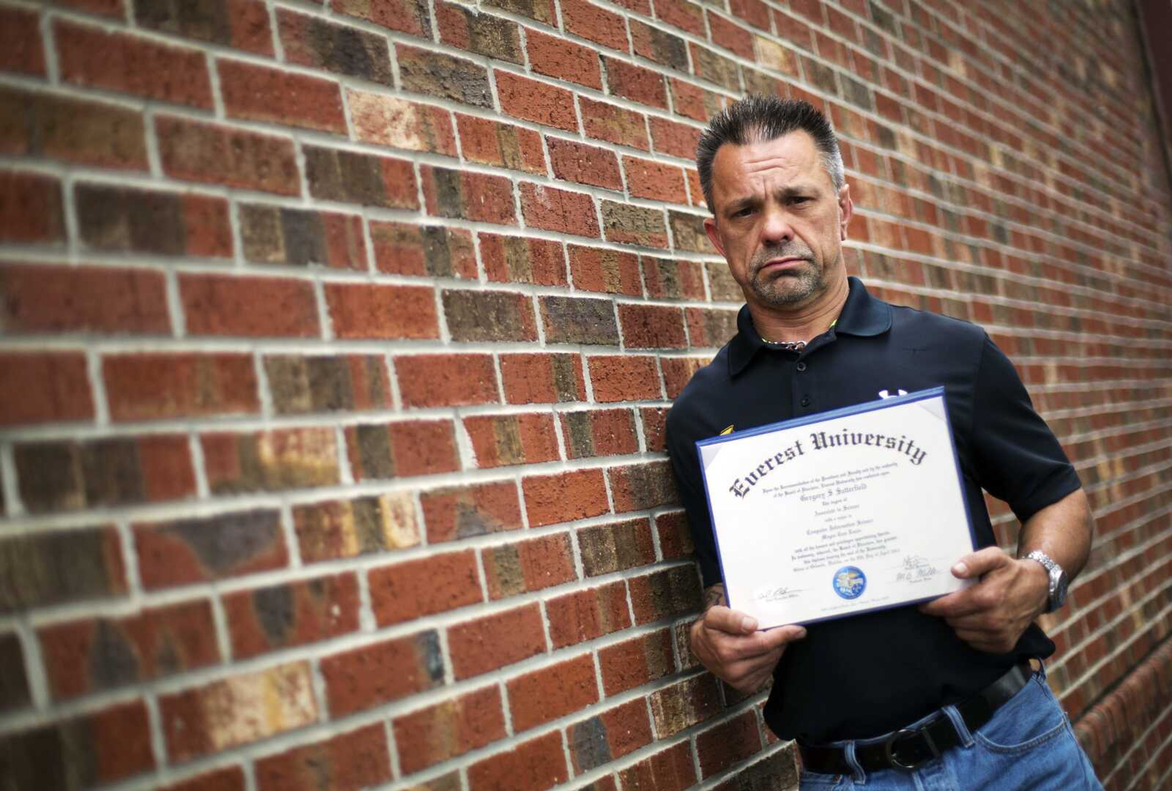 Shane Satterfield, a roofer who owes more than $30,000 in debt for an associate's degree in computer science from one of the country's largest for-profit college companies that failed in 2014, holds his diploma Friday in Atlanta. "I graduated in April at the top of my class, with honors," Satterfield said. "And I can't get a job paying over $8.50 an hour."