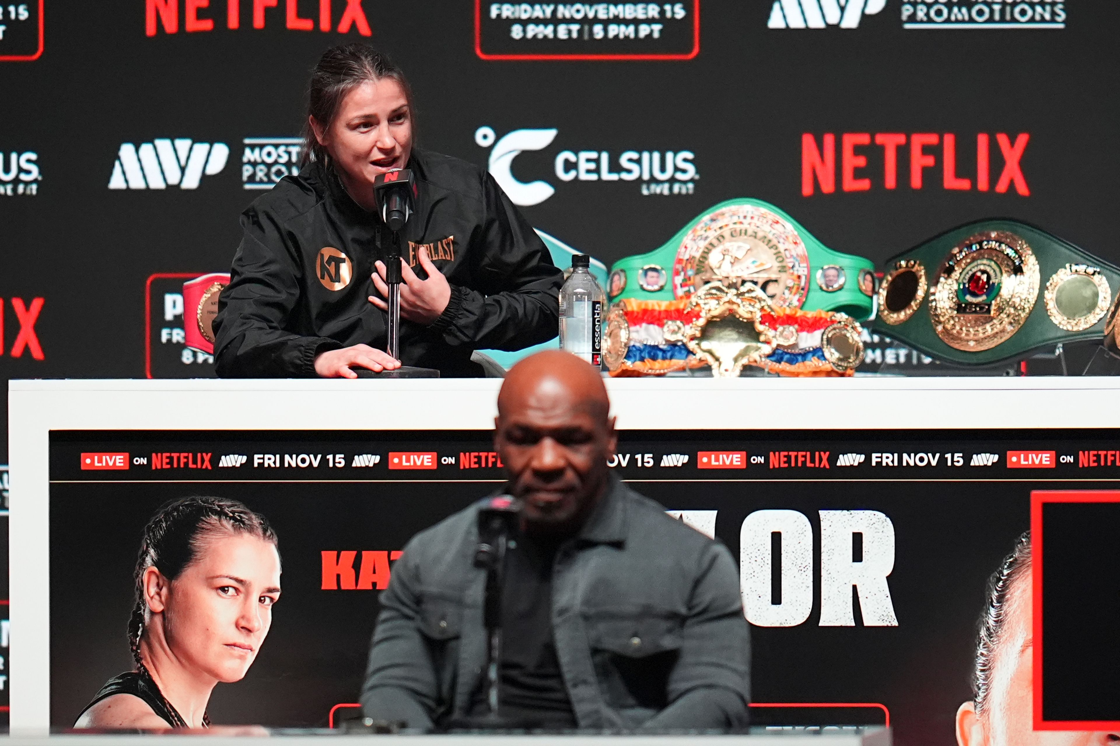 Mike Tyson, bottom, listens as Katie Taylor speaks during a news conference ahead of her undisputed super lightweight world title bout against Amanda Serrano, the co-main event in the Tyson vs. Jake Paul fight night, Wednesday, Nov. 13, 2024, in Irving, Texas. (AP Photo/Julio Cortez)