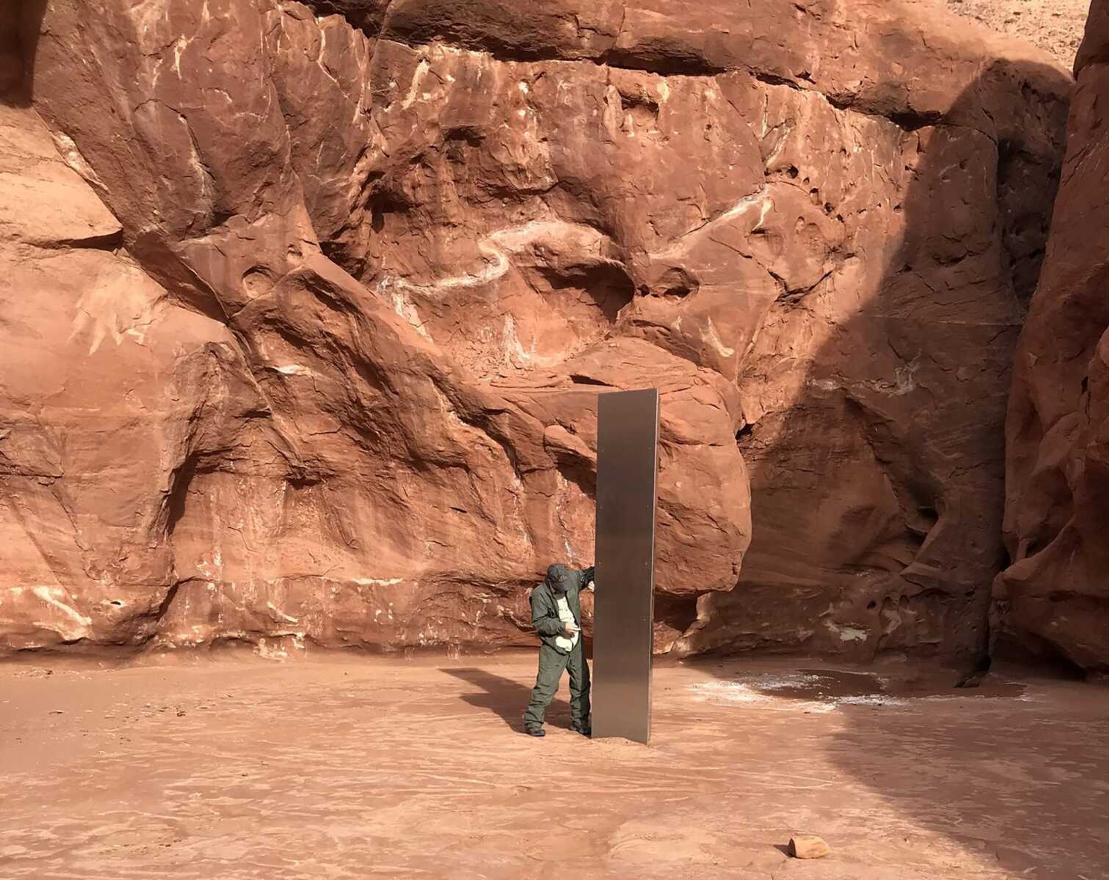 A Utah state worker stands next to a metal monolith in the ground Nov. 18 in a remote area of red rock in Utah.