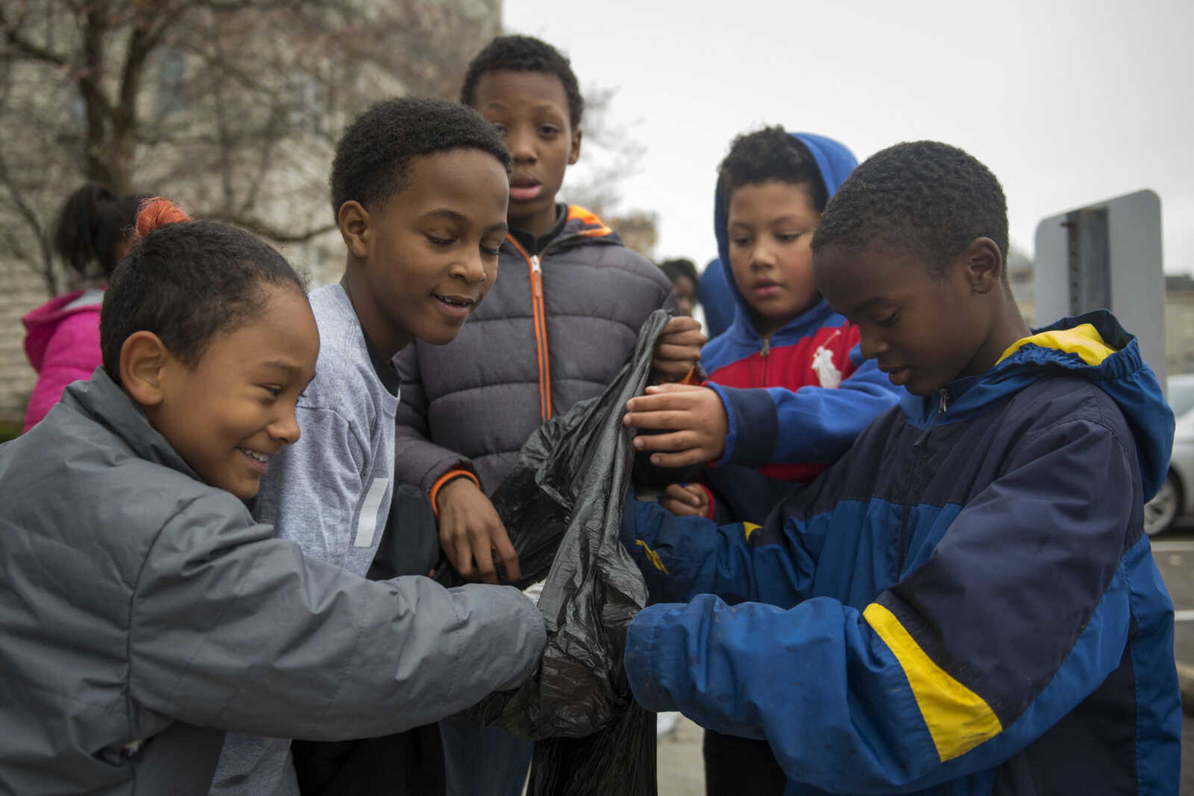 Jefferson Elementary students, from left, Angel Rodriguez, Jykeem Martin, Kevin Miles, Kegan Primer and Jermiah Washington put fill a garbage bag with debris on the Southeast Missouri State University campus as part of a beautification project Monday.