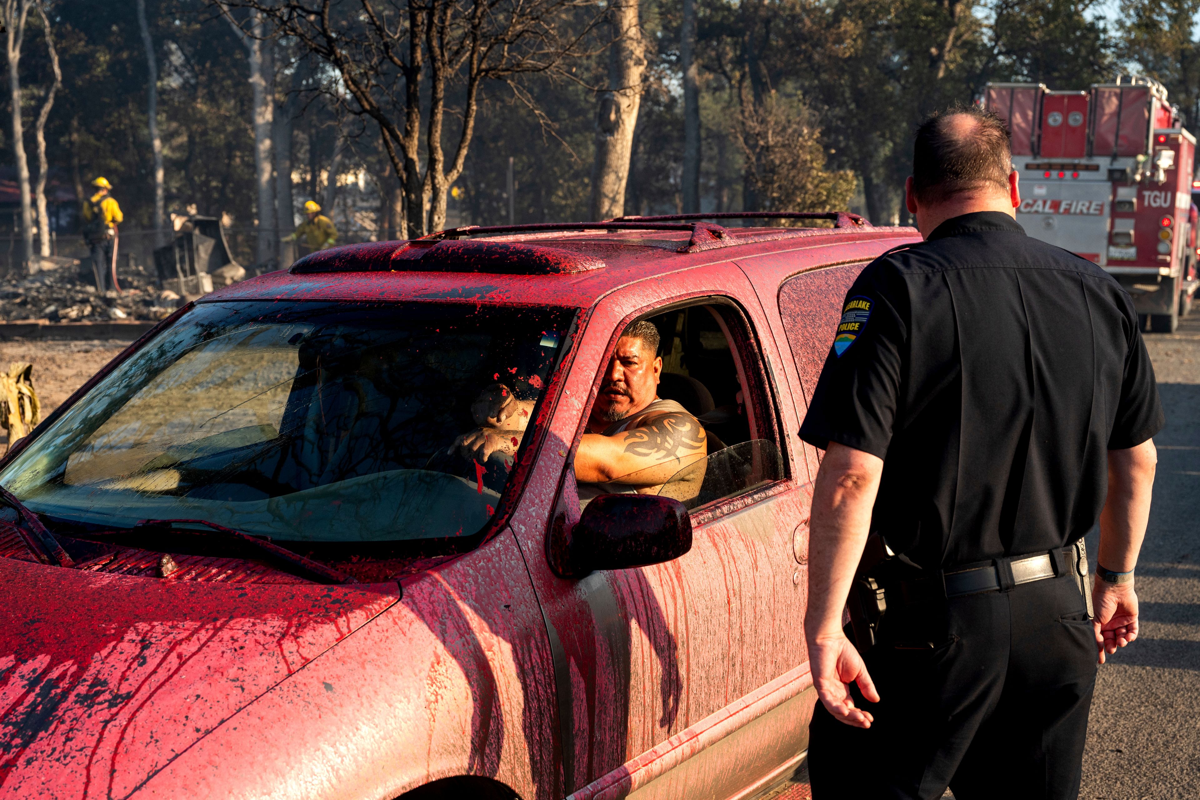 Fire retardant coats Joel Ayon's car as he drives through a neighborhood impacted by the Boyles fire in Clearlake, Calif., on Sunday, Sept. 8, 2024. (AP Photo/Noah Berger)