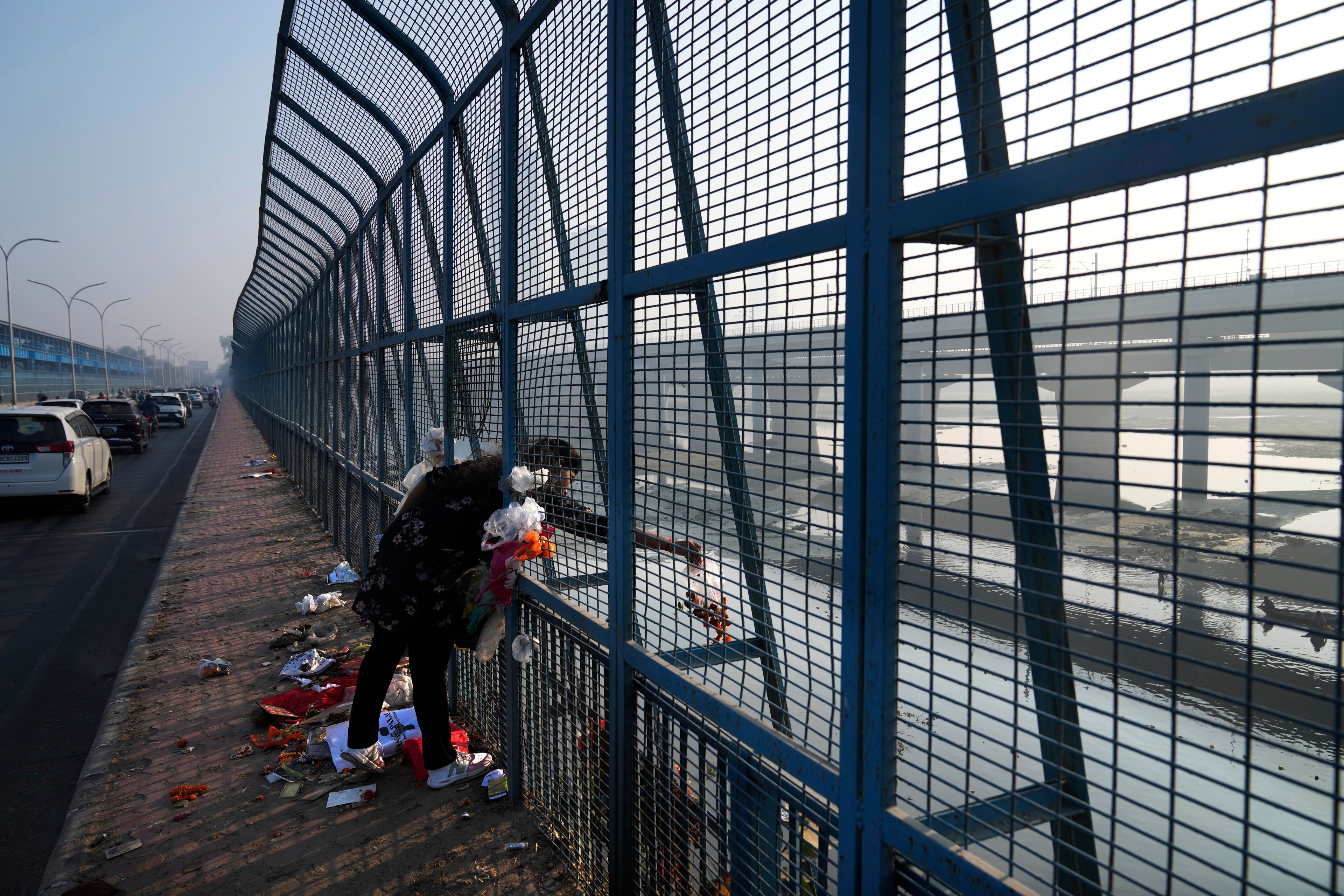 A woman throws used prayer materials in the river Yamuna in New Delhi, India, Tuesday, Oct. 29, 2024. (AP Photo/Manish Swarup)