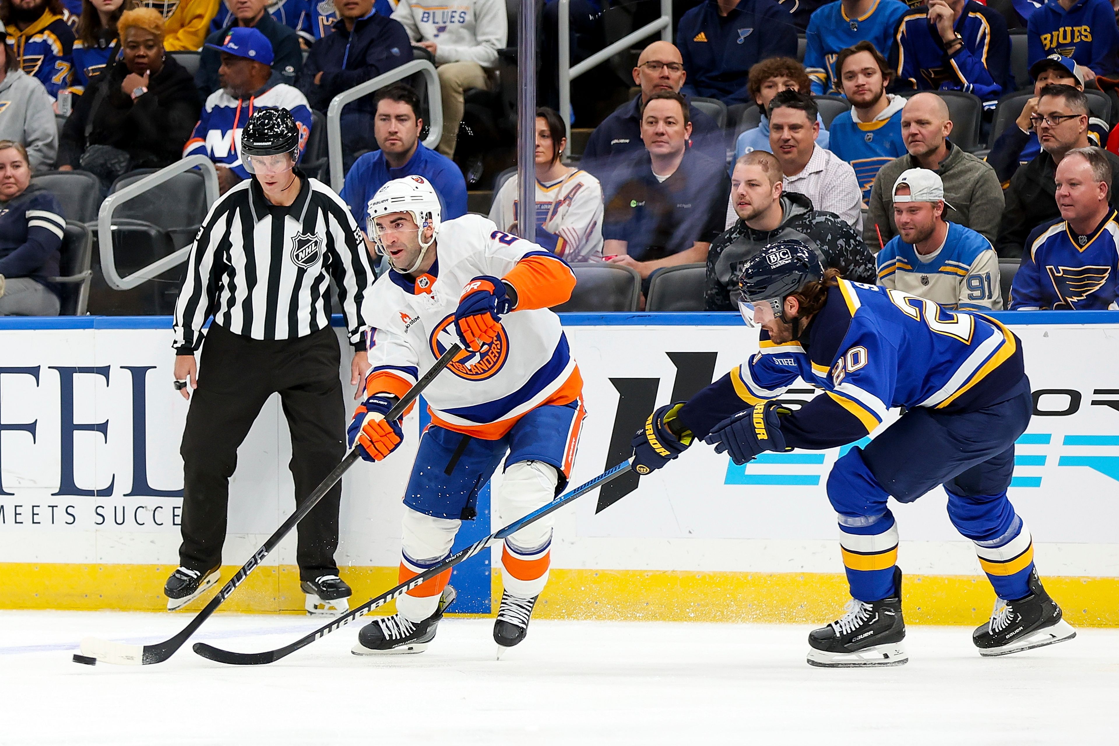 New York Islanders' Kyle Palmieri (21) passes the puck while under pressure from St. Louis Blues' Brandon Saad (20) during the first period of an NHL hockey game Thursday, Oct. 17, 2024, in St. Louis. (AP Photo/Scott Kane)