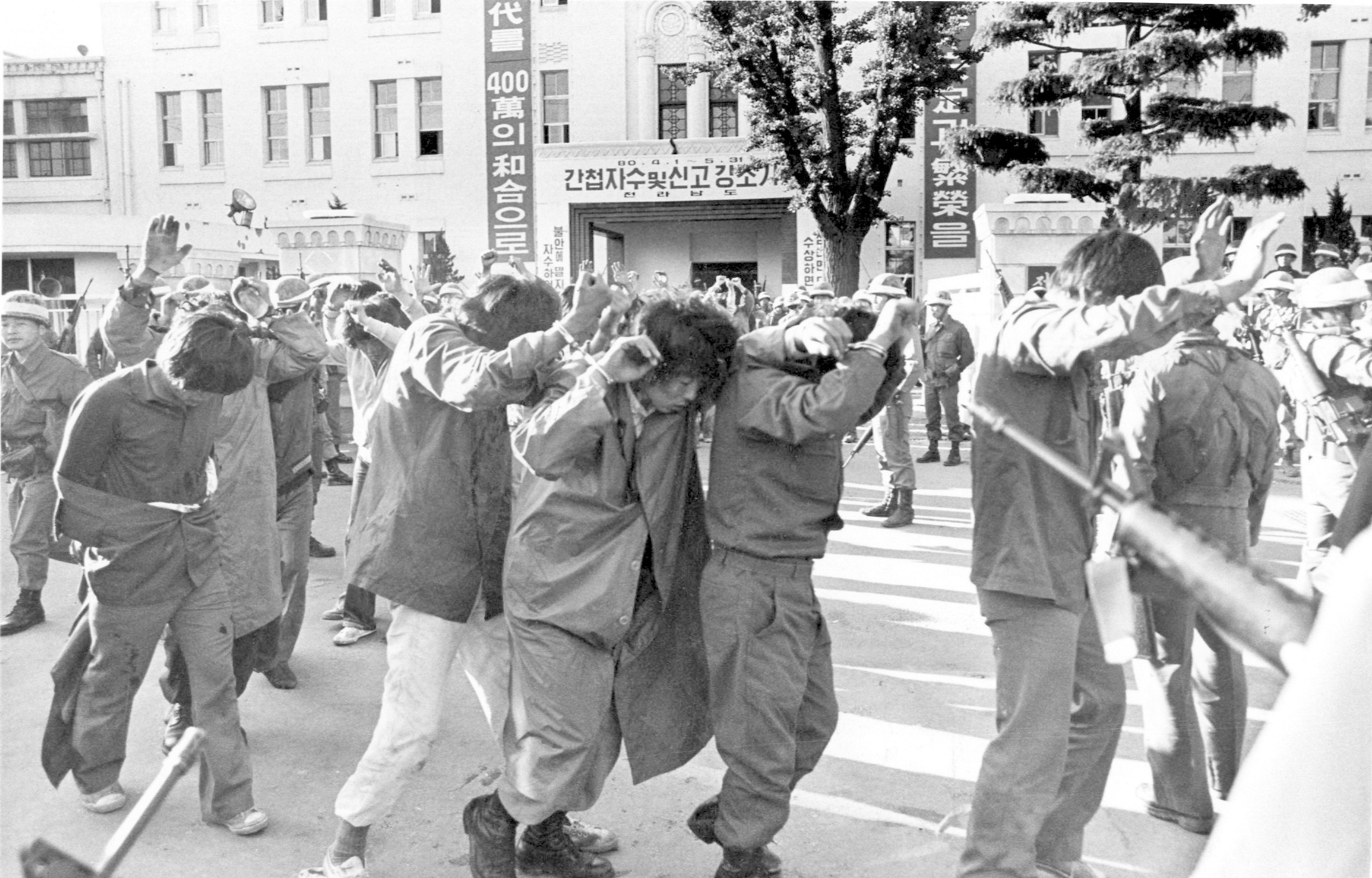 FILE- Scores of captured rebels with hands up are being led away Tuesday May 27, 1980, by armed soldiers from the provincial government HQ., in this city of Gwangju (Kwangju) which South Korean troops recaptured in a firefight earlier in the day. (AP Photo)