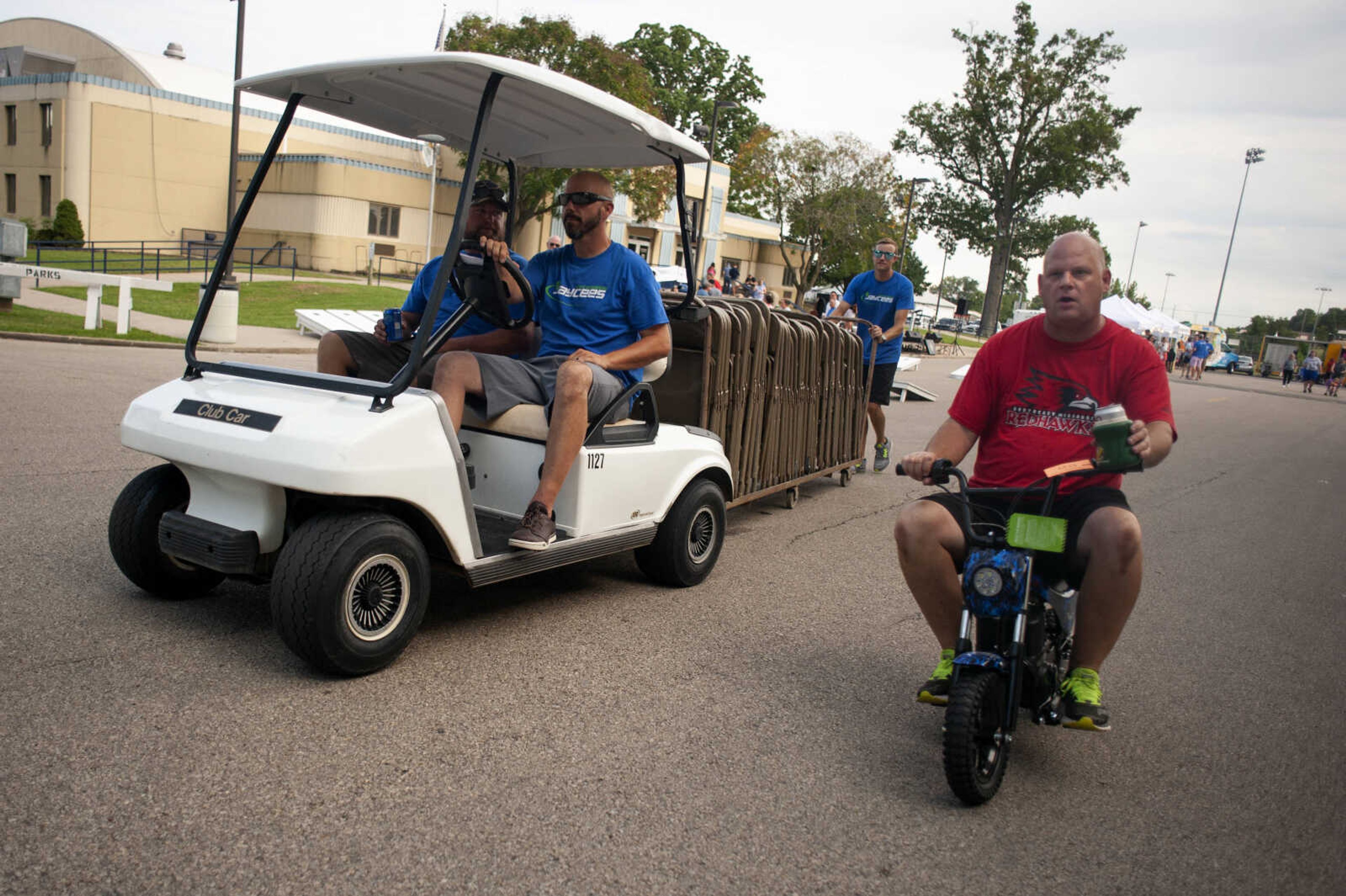 Todd Rapp of Jackson, right, passes a golf cart on a small motorized bike during the 27th annual Cape Jaycees BBQ Fest on Friday, Aug. 16, 2019, at Arena Park in Cape Girardeau.