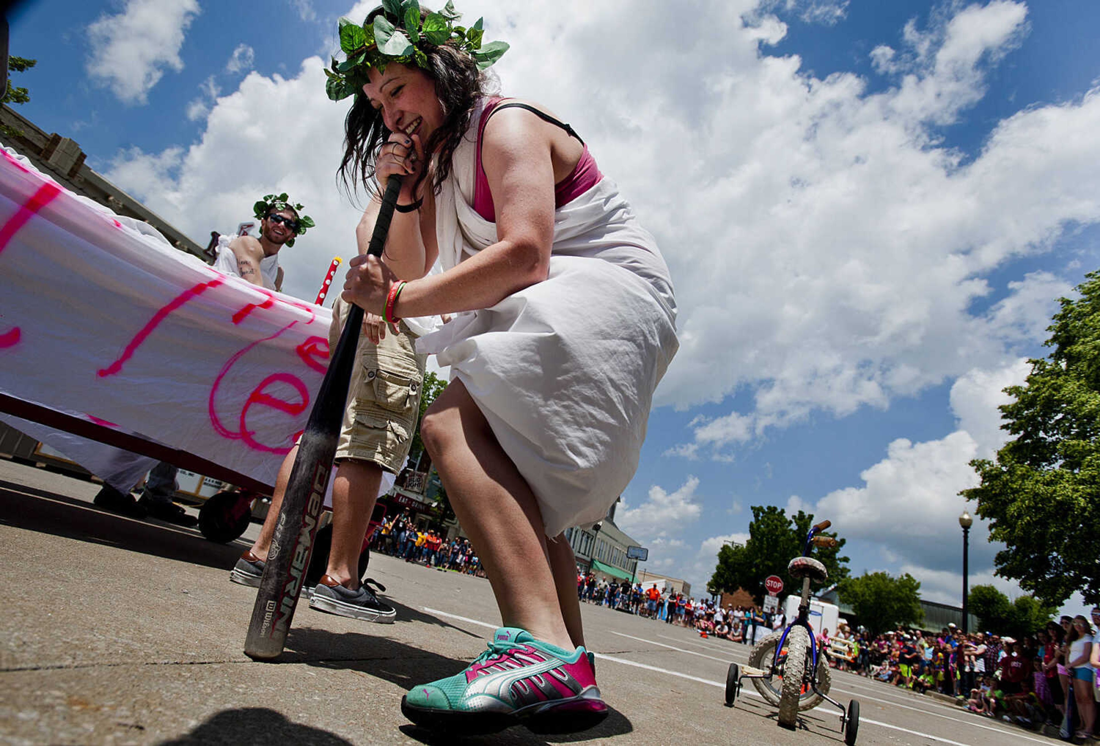 Ashley Reid spins around on a baseball bat before riding a children's bike through an obstacle course during the first segment of the Perryville Mayfest Bed Races Saturday, May 10, in Perryville, Mo. Reid was a member of the Animal House team sponsored by Mary Jane, Burgers and Brew.