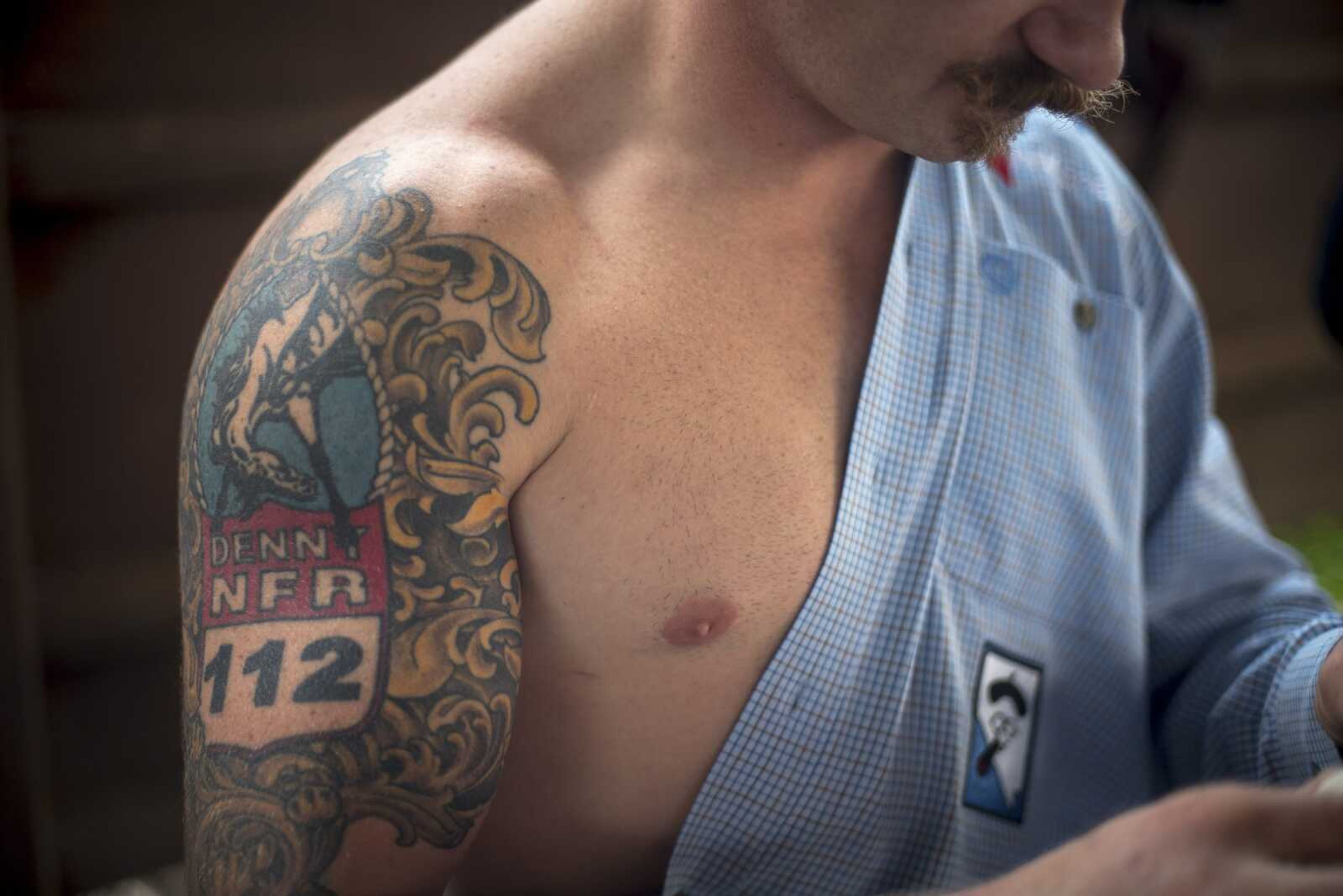 Wyatt Denny's tattoo is seen while he tapes up his arms in preparation for the bareback horse riding competition during the Sikeston Jaycee Bootheel Rodeo Wednesday, Aug. 7, 2019, in Sikeston.