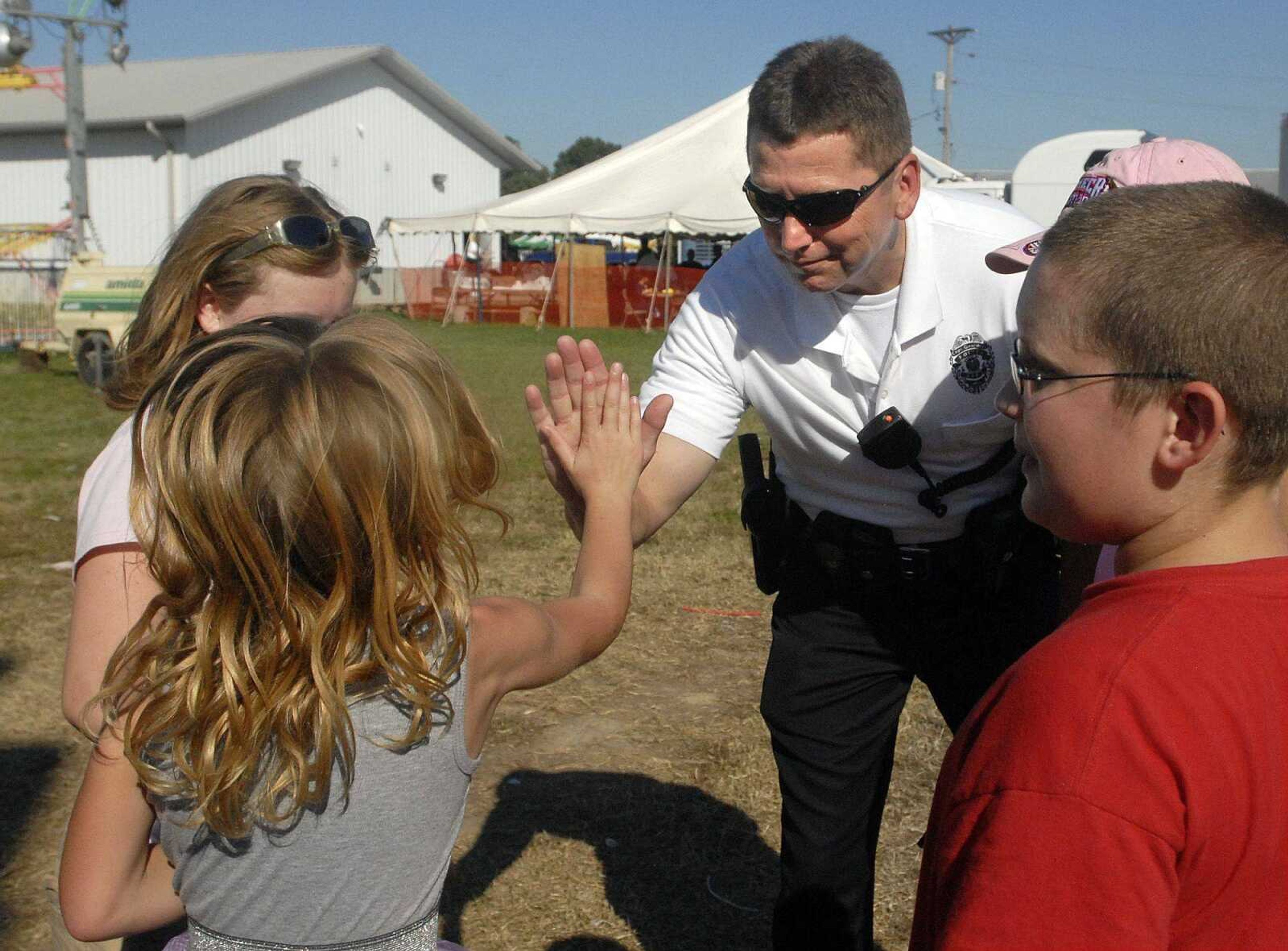 Lt. Rick Price of the Cape Girardeau Police Department high-fives 7-year-old Karabeth Hale after returning her and her twin sister and cousin to their guardian Saturday during the final day of the SEMO District Fair. (Laura Simon)